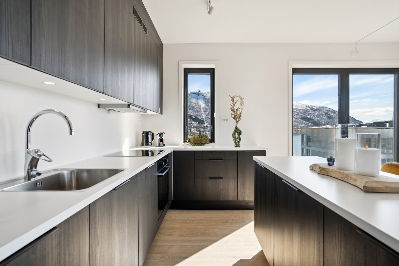 Moderne, sort kjøkken med integrerte hvitevarer, kjøkkenøy og god skap- og benkeplass. Galleribilde