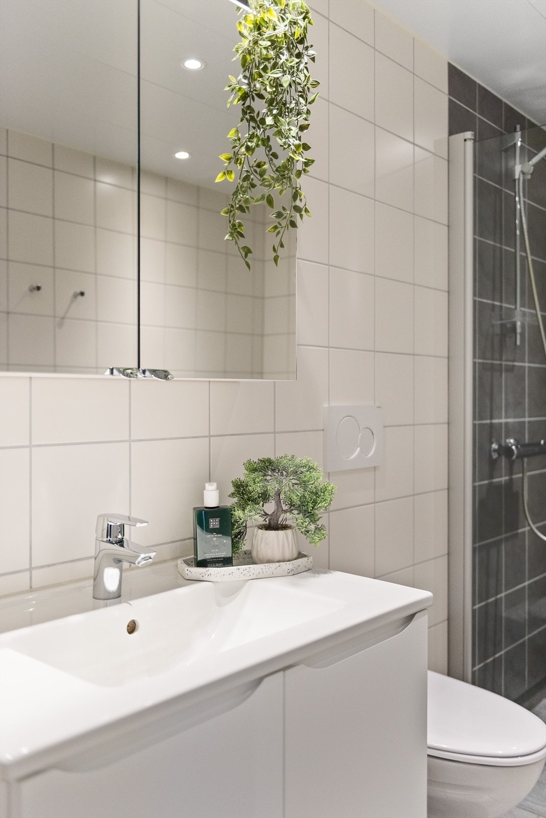 Tidløs baderomsinnredning med lyse fronter og heldekkende servant, samt vegghengt speilskap over. Galleribilde