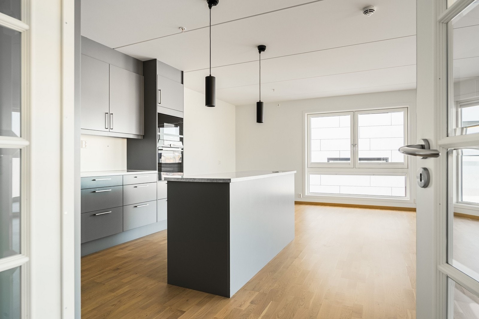 Åpen kjøkken-stueløsning med kjøkkenøy som gir ekstra benkeplass, samt lagringsplass. Galleribilde