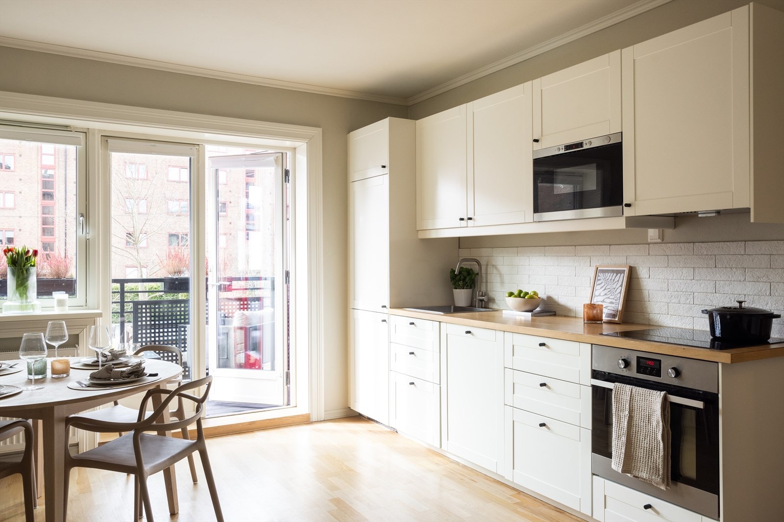 Flott og tidløst kjøkken med hvite, glatte fronter og benkeplate av heltre med nedfelt vaskekum. Galleribilde