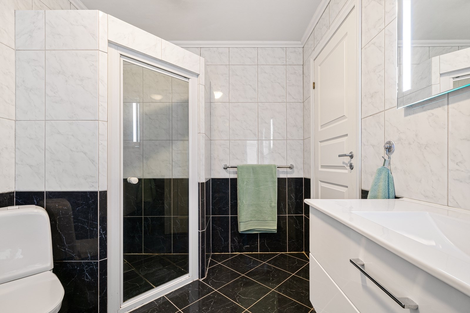 Badet er utstyrt med romslig dusjnisje, toalett, servant med møblement, speil og belysning. Galleribilde