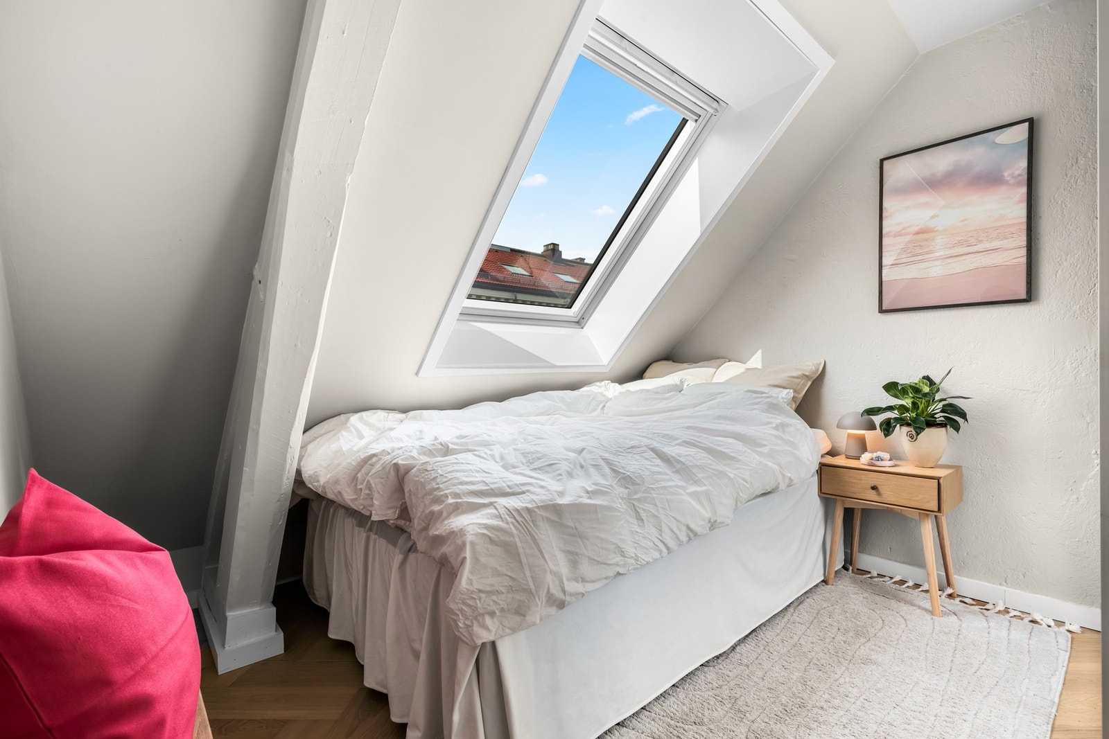 Soverommet er lyst og trivelig med takvindu, lysmalte, glatte vegger, malte, rustikke bjelker og pen fiskebensparkett på gulvet Galleribilde