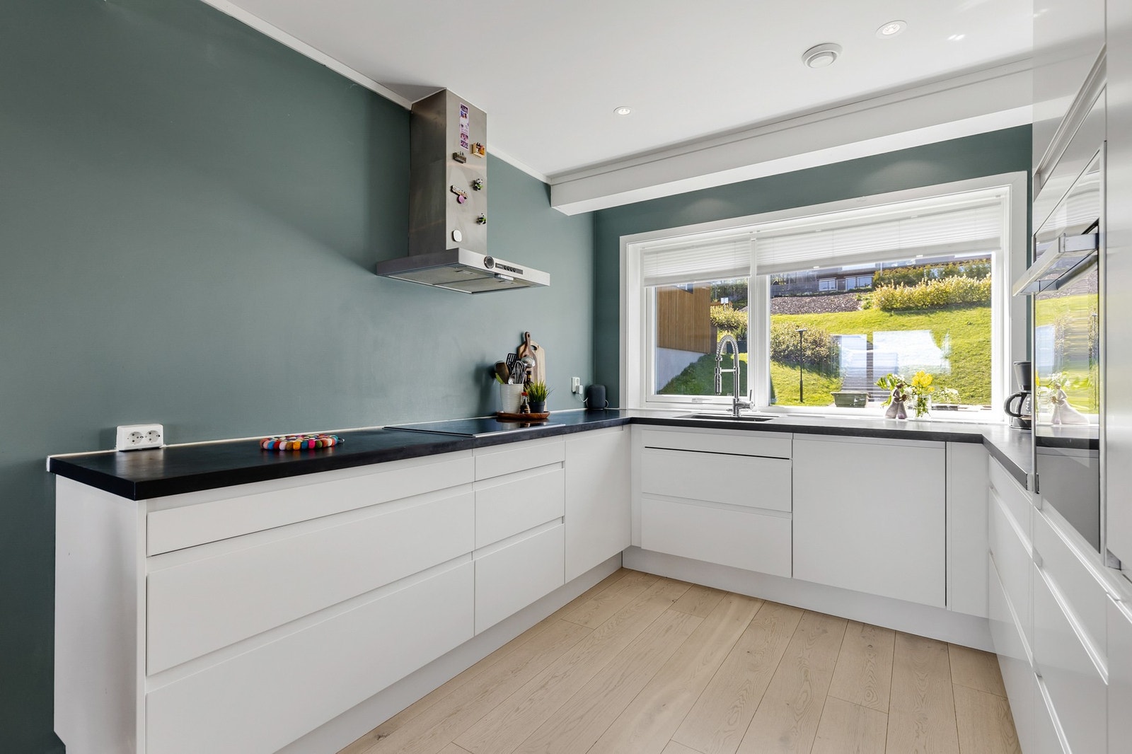 Lysinnslipp fra vinduene gir kjøkkenet et åpent og innbydende preg Galleribilde