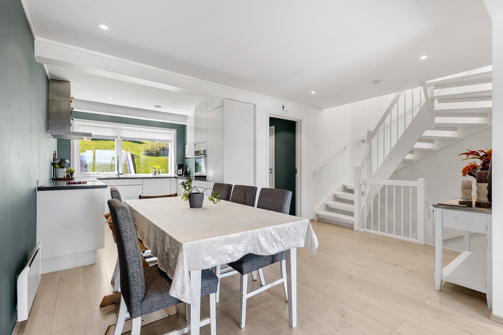 Lyst og innbydende allrom med åpen løsning mellom kjøkken og spiseplass Galleribilde