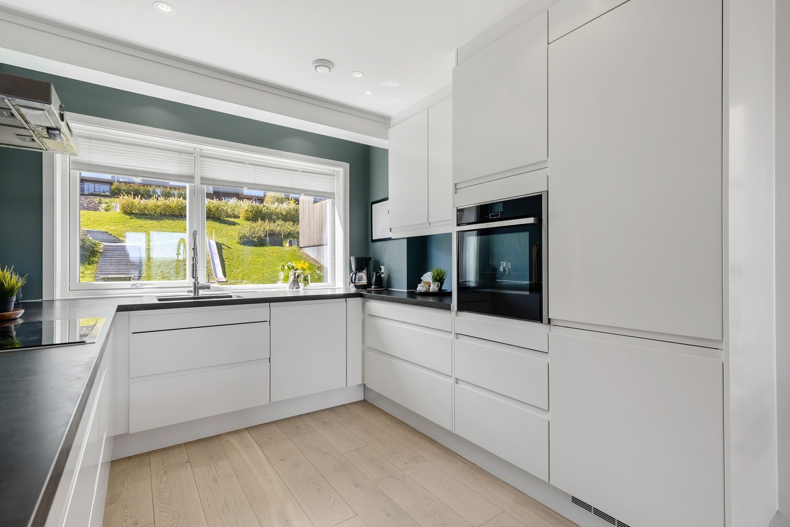 Åpent og moderne kjøkken med slette fronter, integrerte hvitevarer og parkett på gulv Galleribilde