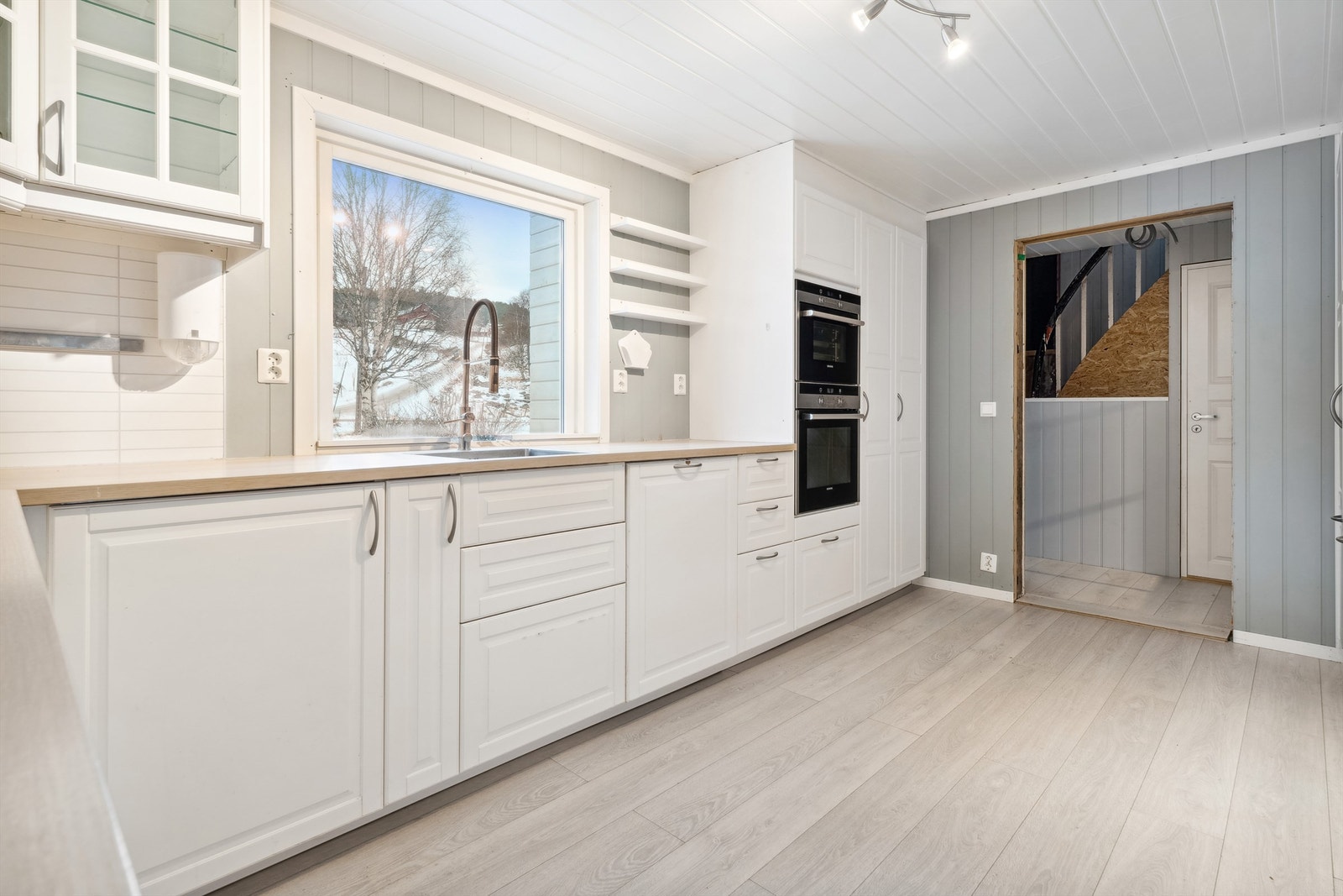 Lys innredning med profilerte fronter og laminat benkeplate med nedfelt oppvaskkum i stål. Galleribilde