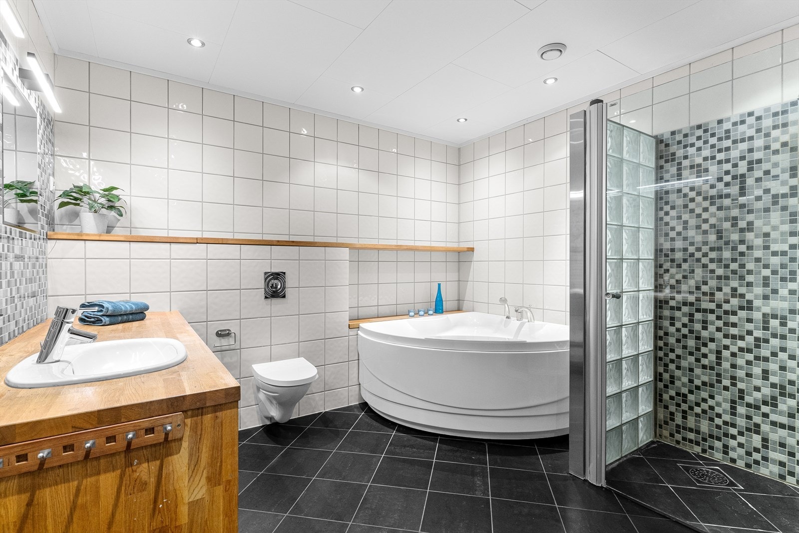 Badet har innredning med nedfelt servant, veggmontert toalett, badekar og dusjvegger/hjørne. Gulvet er fliselagt med elektriske varmekabler, vegger er fliselagt og himling har himlingsplater. Galleribilde