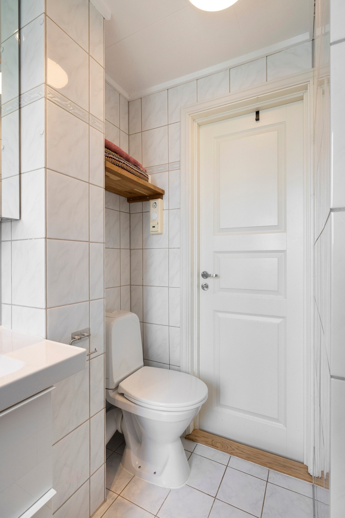 Innredningen inkluderer en servant med slette fronter, gulvstående toalett, dusjkabinett og opplegg for vaskemaskin Galleribilde