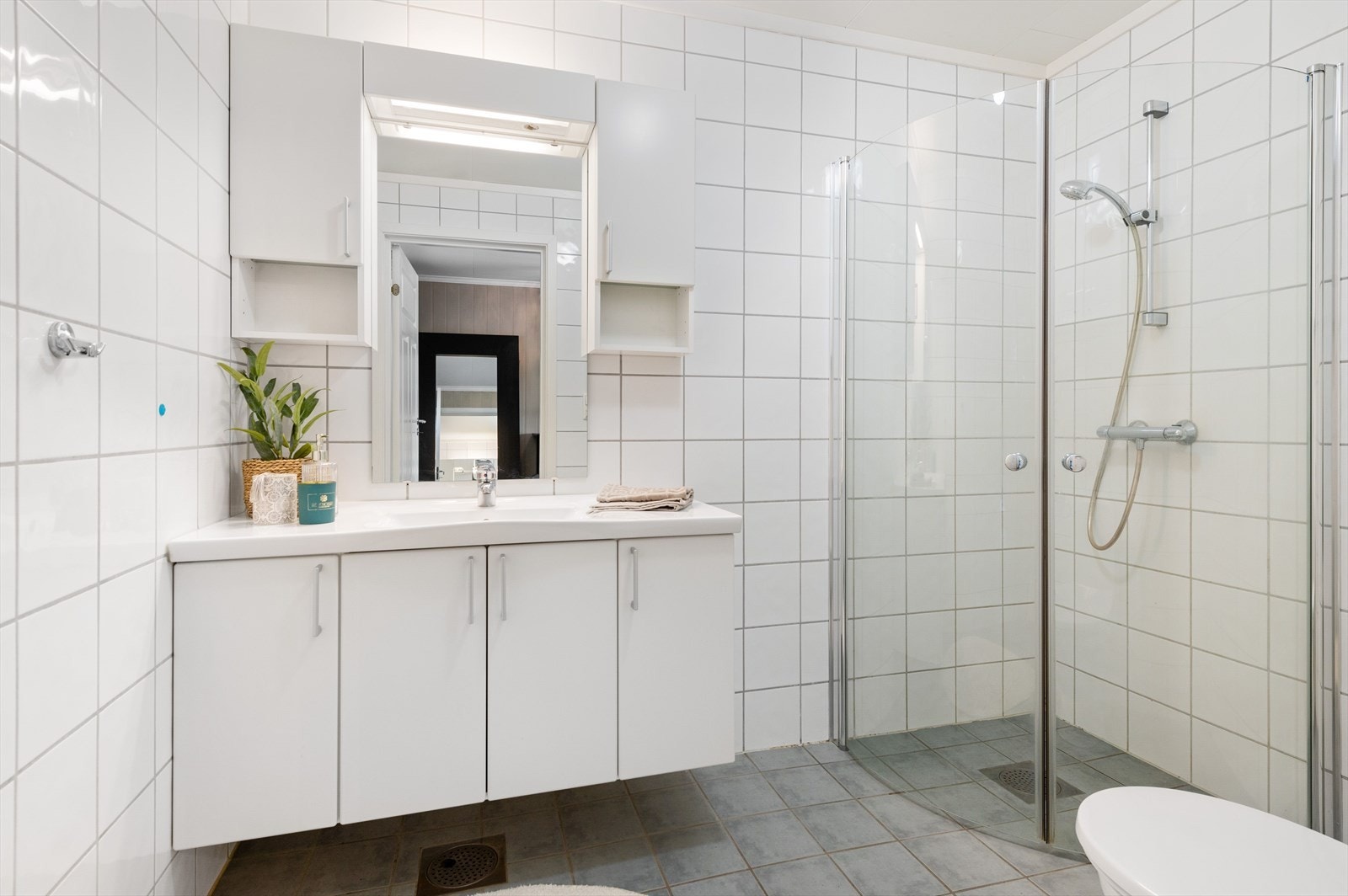 Lyst og pent bad fra byggeåret med lys innredning, dusjhjørne og gulvmontert toalett. Galleribilde