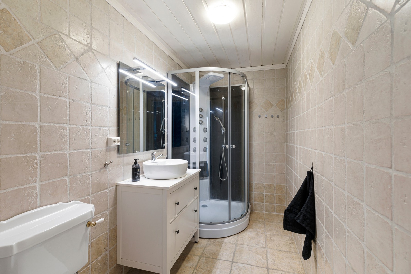 Ett av badene i etasjen har tilkomst fra gang. Badet ble oppusset i 2007 og har flislagt gulv og vegger. Rommet er videre utstyrt med varmekabler i gulv, dusjkabinett, toalett og baderomsinnredning med servant og speil. Galleribilde