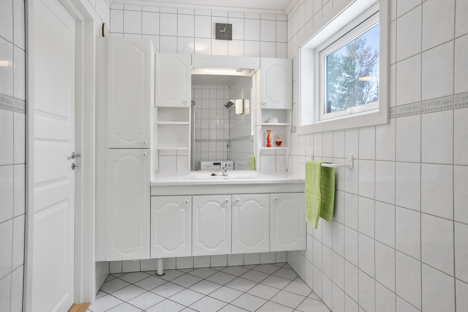 Badet i hovedetasjen er flislagt, med vegghengt toalett, dusjhjørne og innredning med servant og oppbevaringsplass. Galleribilde