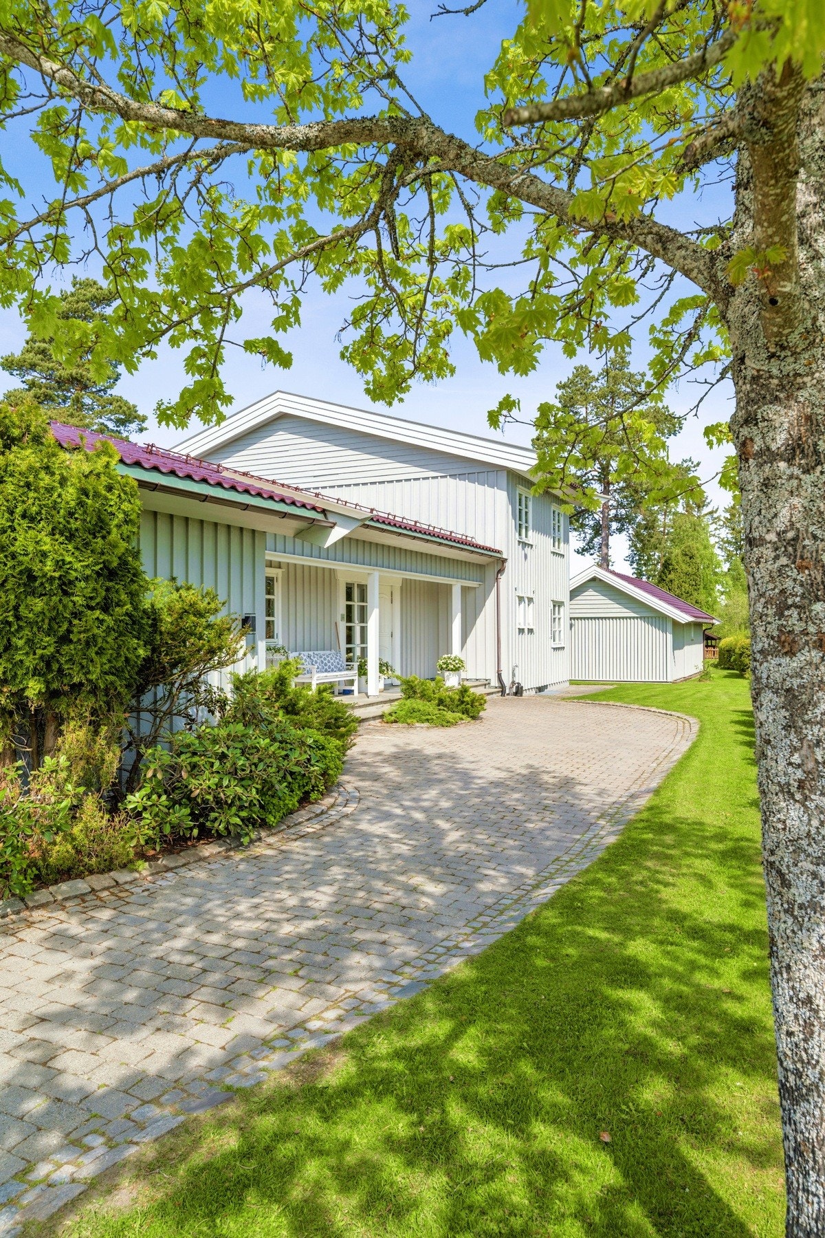 Tidløs og innbydende fasade med overbygd inngang, vakre detaljer og omkranset av frodig beplantning. Galleribilde