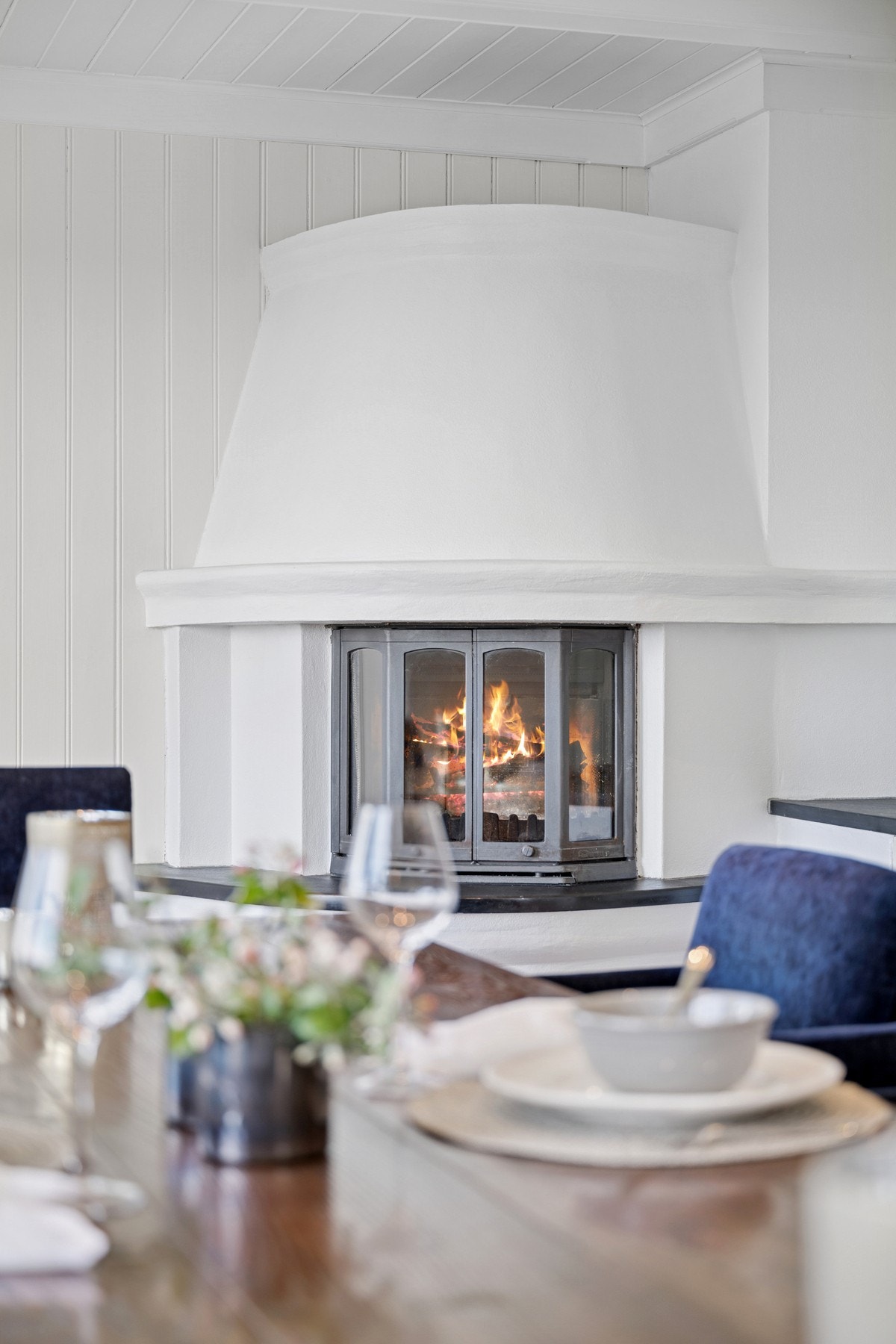 Den klassiske peisen skaper lun stemning og markerer overgangen mellom kjøkken og spiseplass på elegant vis. Galleribilde