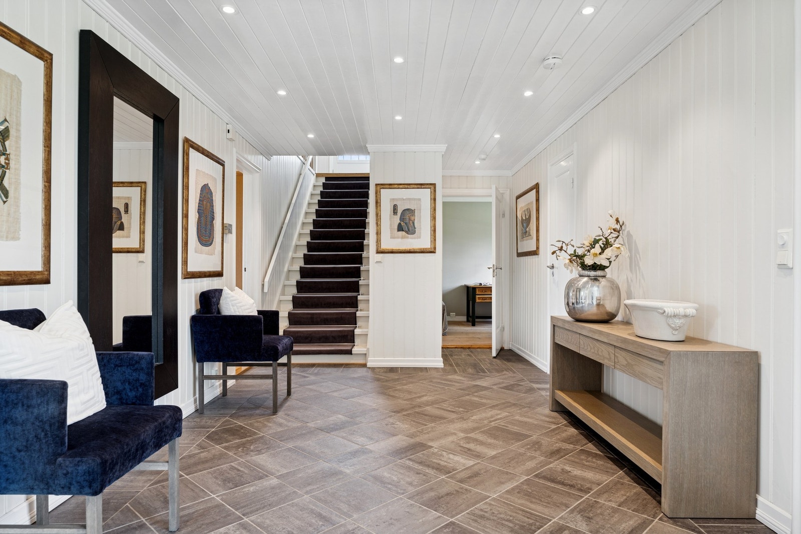 Lys og luftig hall med praktisk skyvedørsgarderobe og gjennomgang til husets hovedsoner. Galleribilde