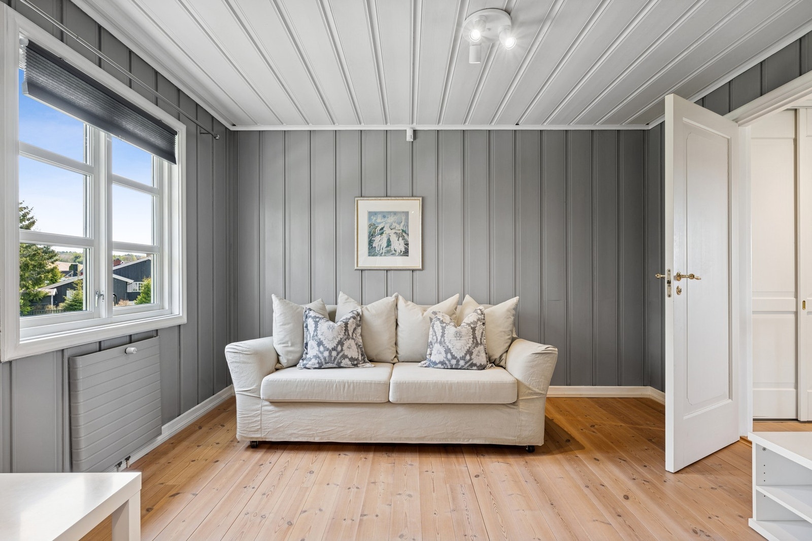 Trivelig krok med plass til sofa og møbler - perfekt som sosial sone eller ekstra oppholdsrom. Malte panelvegger i moderne grånyanse. Galleribilde