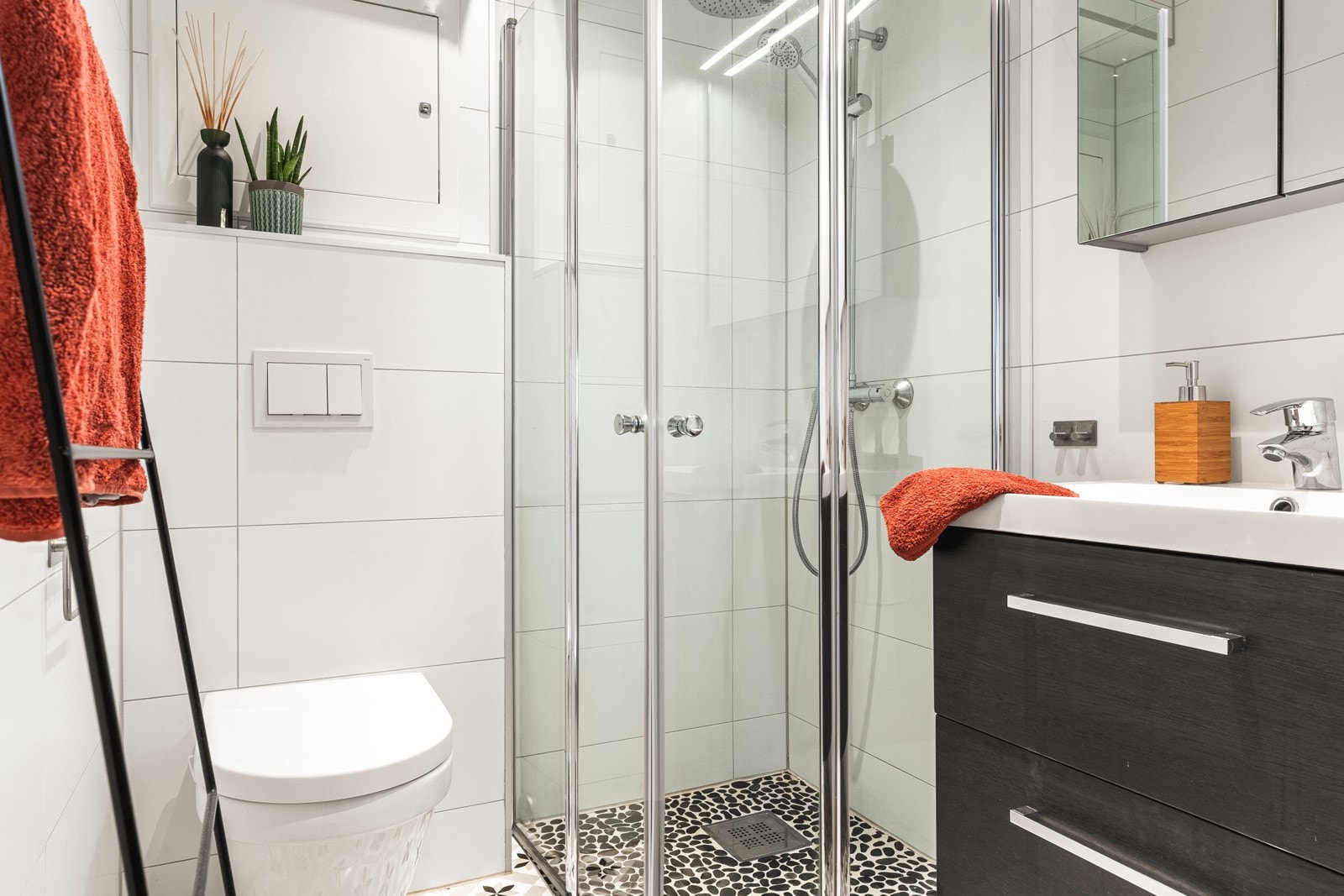 Badet er helfliset med varmekabler i gulv og har en slett malt himling. Badet er innredet med dusj med glassvegger, vegghengt toalett og baderomsinnredning. Galleribilde