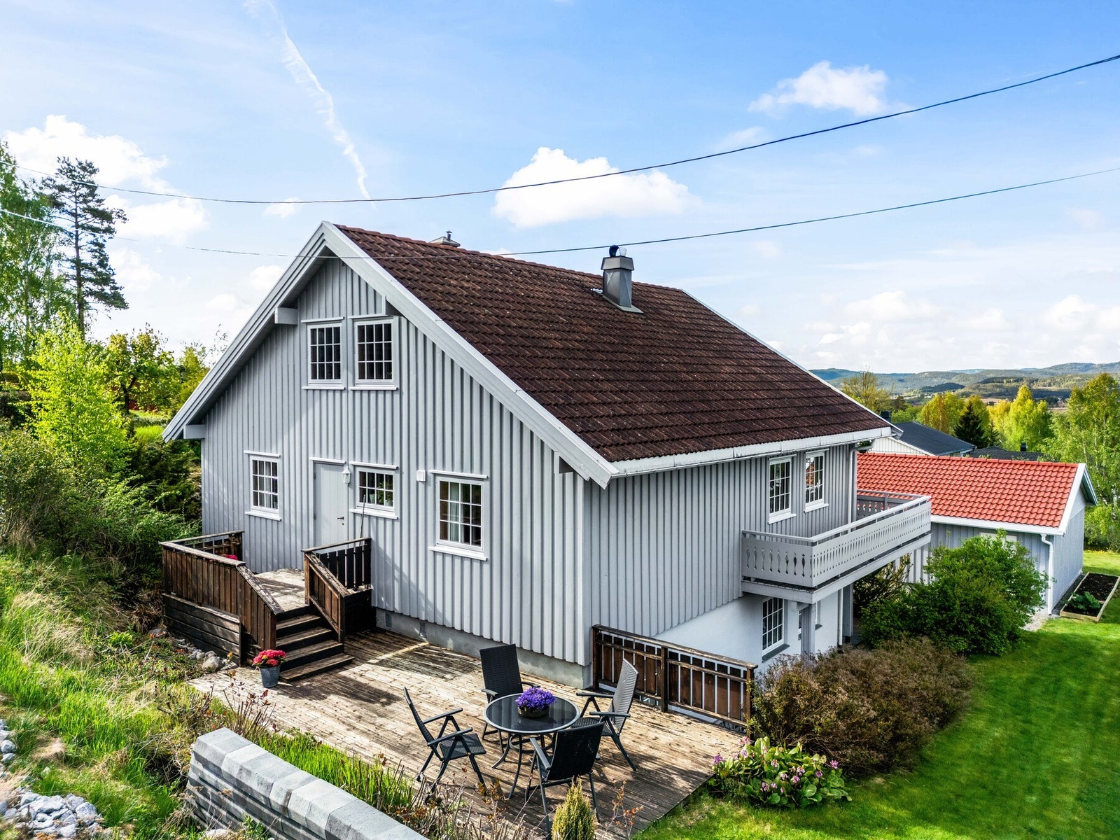 Tomten er fint opparbeidet med plen, beplantning og flere sitteplasser. Galleribilde