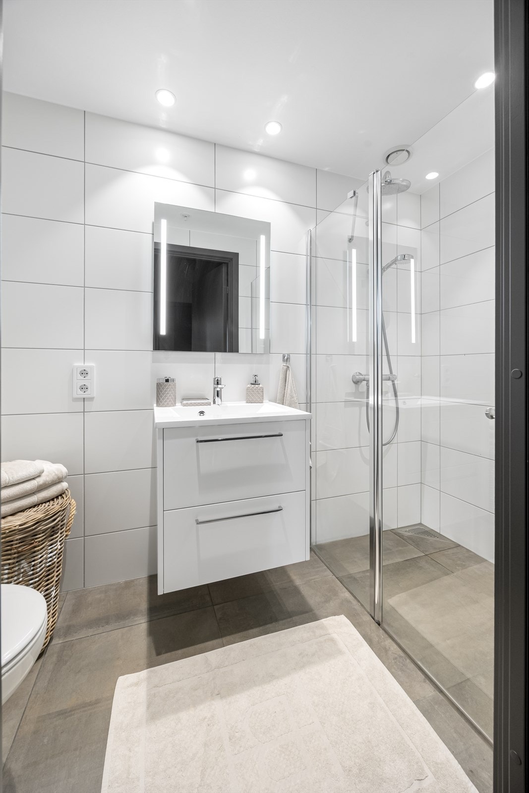 Gjestebad med fliser til tak, vegghengt toalett, servantinnredning og dushjørne. Galleribilde