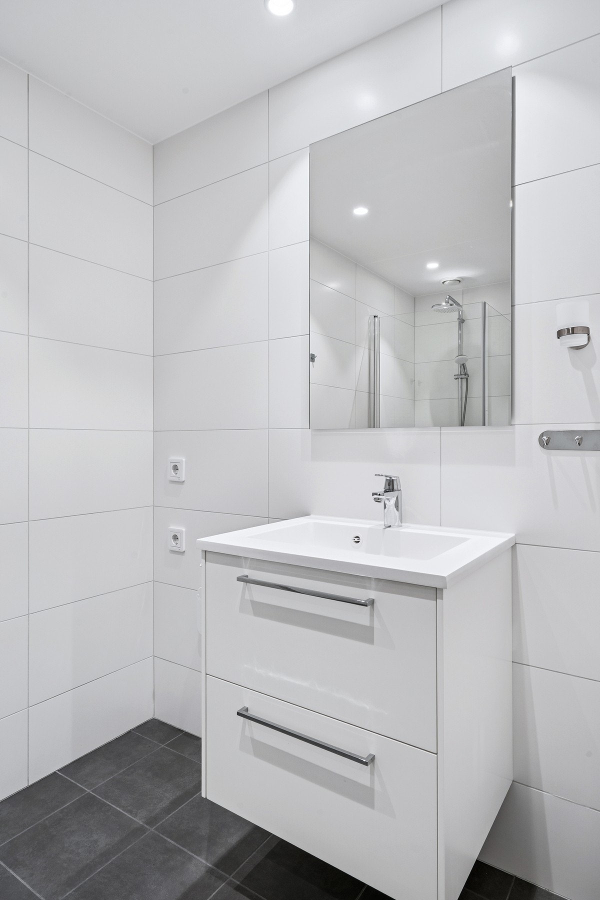 Badet er klargjort for vaskemaskin, og med praktiske oppheng og belysning som gjør hverdagen enklere. Galleribilde