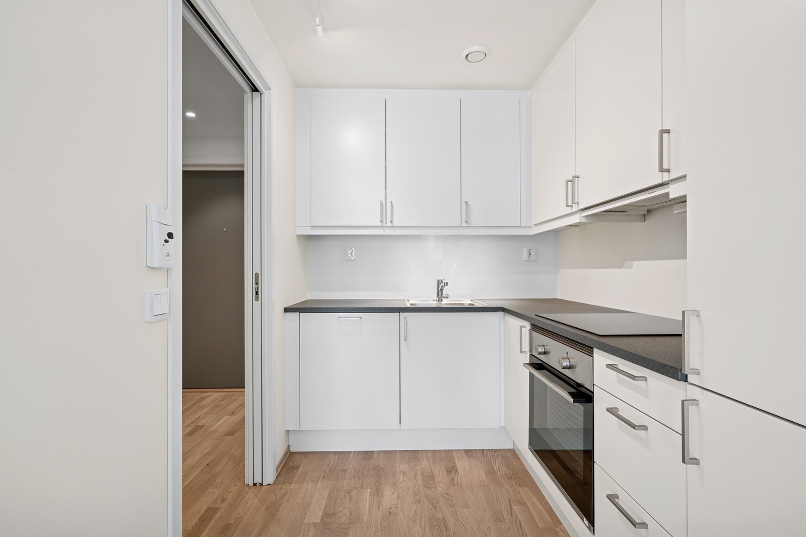 Kjøkkenet fra Sigdal Studio (2024) har et stilrent uttrykk med lyse fronter og mørk benkeplate. Galleribilde