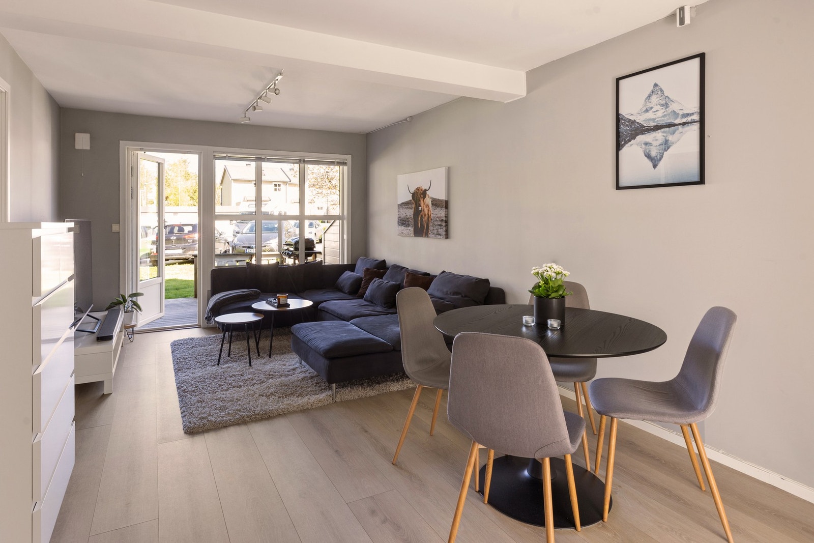 Stuen har store vinduer som gir masse naturlig lys. Det er praktisk fordelt med sofa og tv Galleribilde