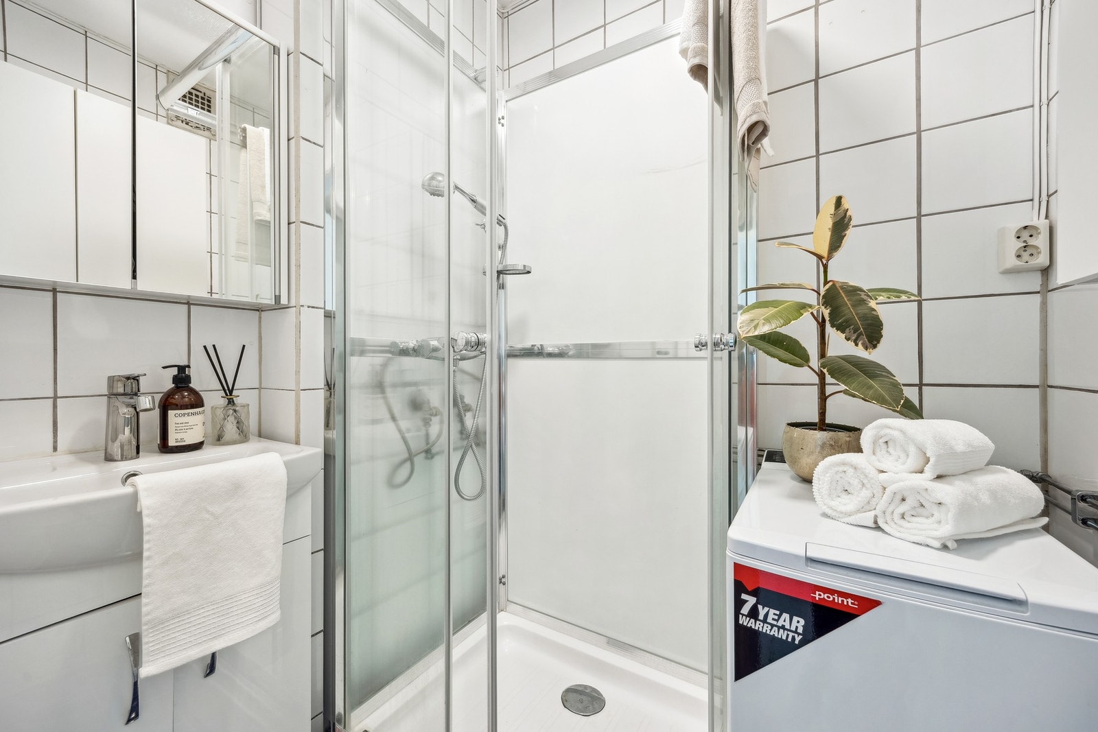 Flislagt bad med gulvvarme, vegghengt servant, speilskap med overlys og dusjkabinett. Galleribilde