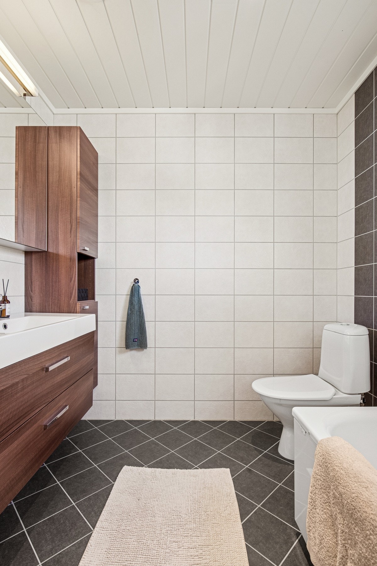 Romslig bad med servant og underskap, speilskap med belysning, to høyskap for ekstra oppbevaring, badekar, gulvmontert toalett og balansert ventilasjon. Galleribilde