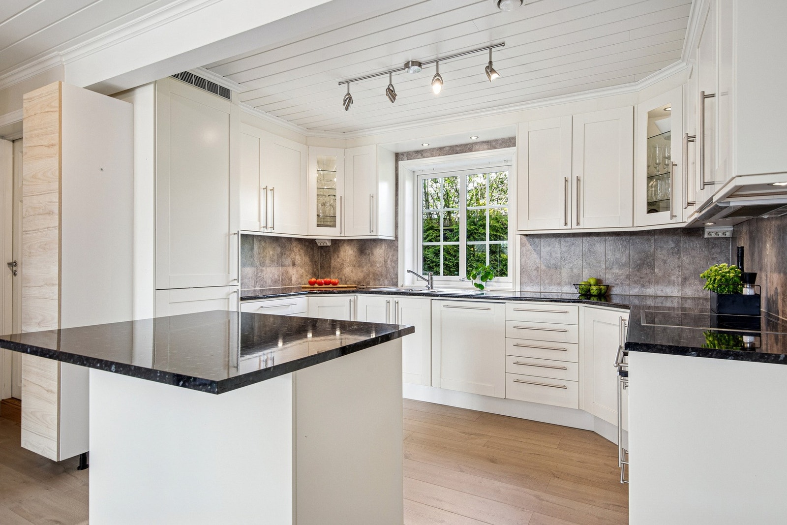 Kjøkkenet er både pent og praktisk, med profilerte fronter, laminerte skrog og fliser mellom benk og overskap for et stilrent uttrykk. Galleribilde