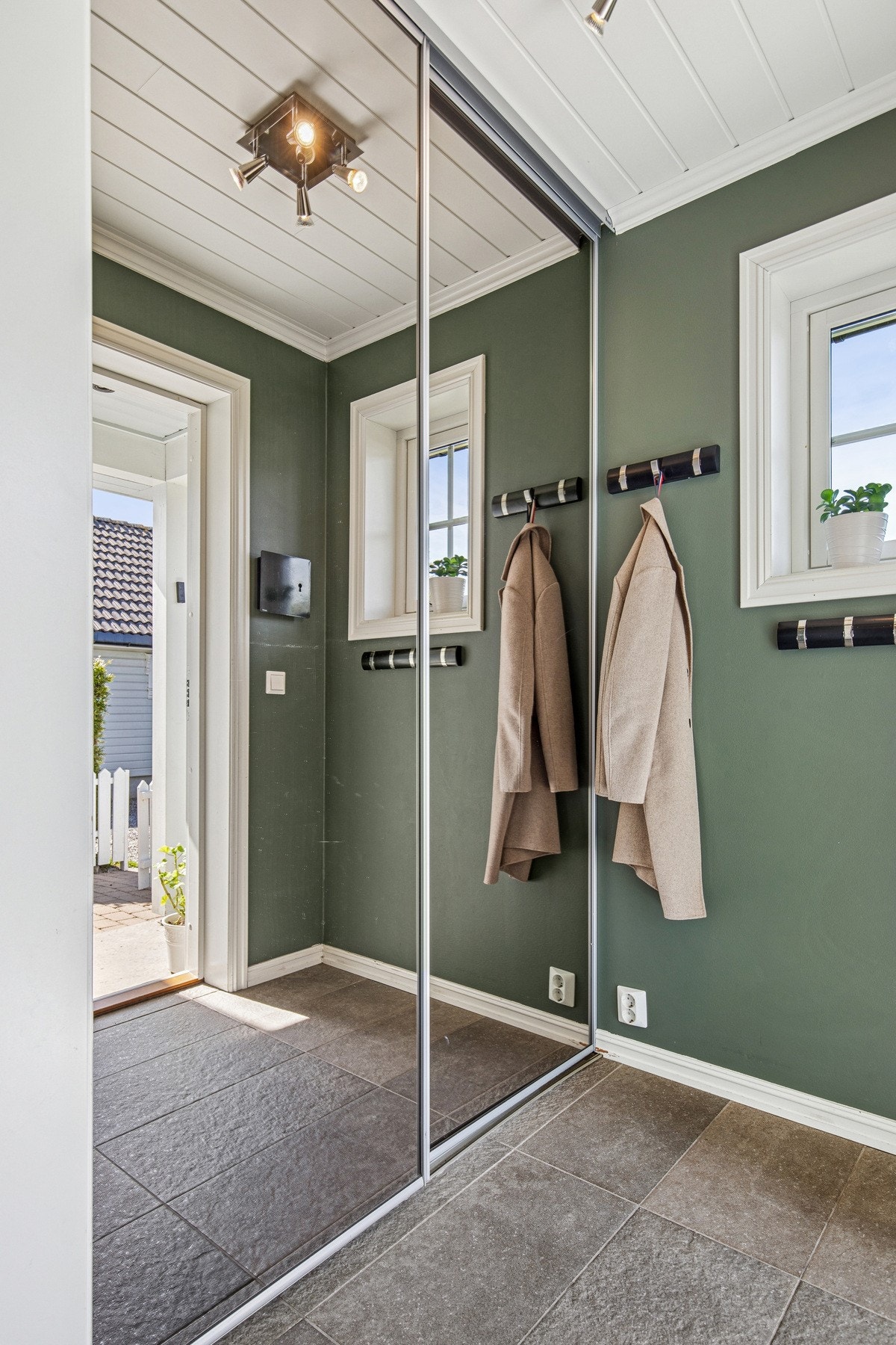 Innenfor døren blir du møtt av en romslig og lys entré med flislagt gulv, praktisk dobbel skyvedørsgarderobe med speilfronter og tidsriktige farger på veggene. Galleribilde