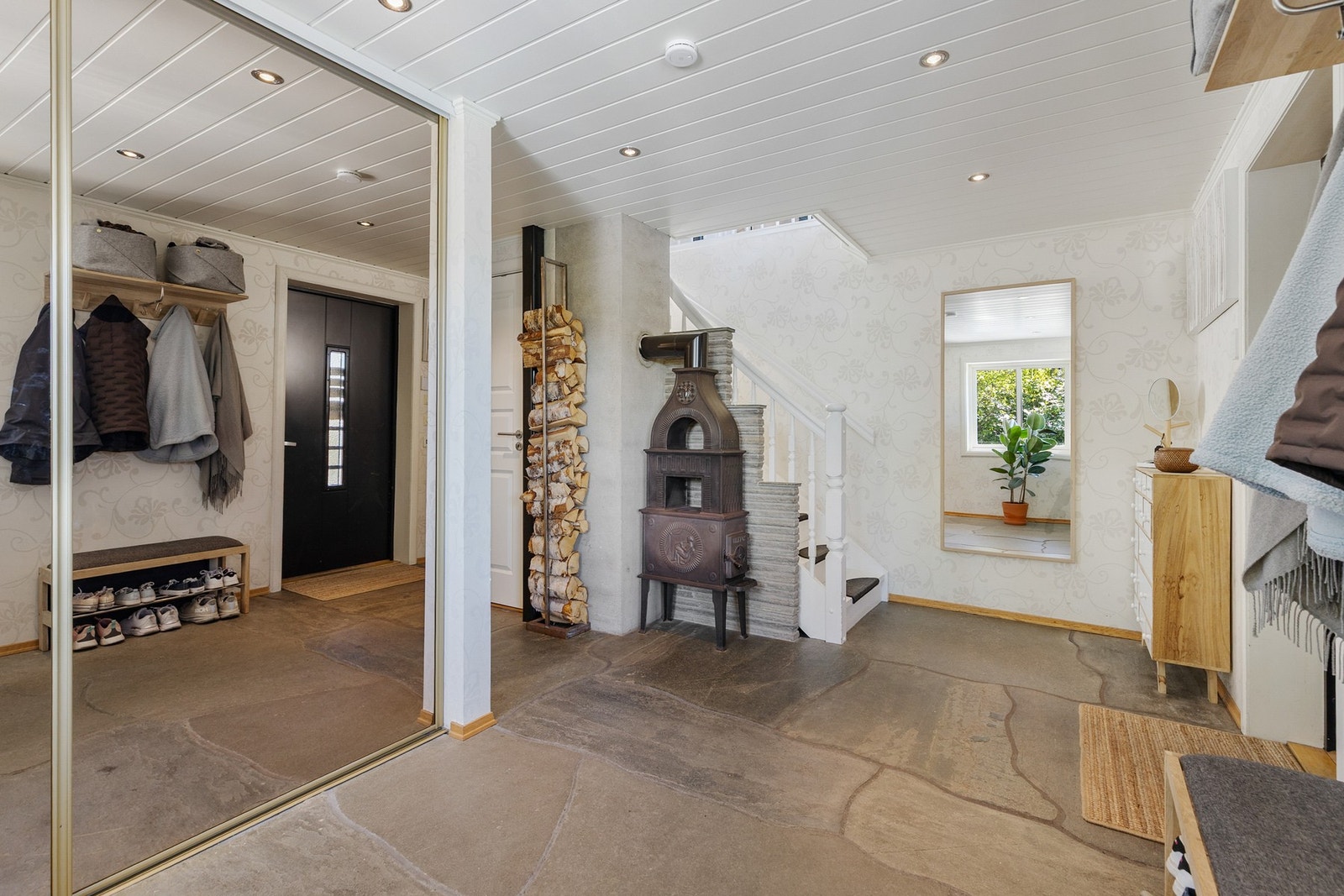 Romslig entré/hall med skifer/stein på gulv, tapetserte flater på vegger og malt panel i himling med downlights Galleribilde