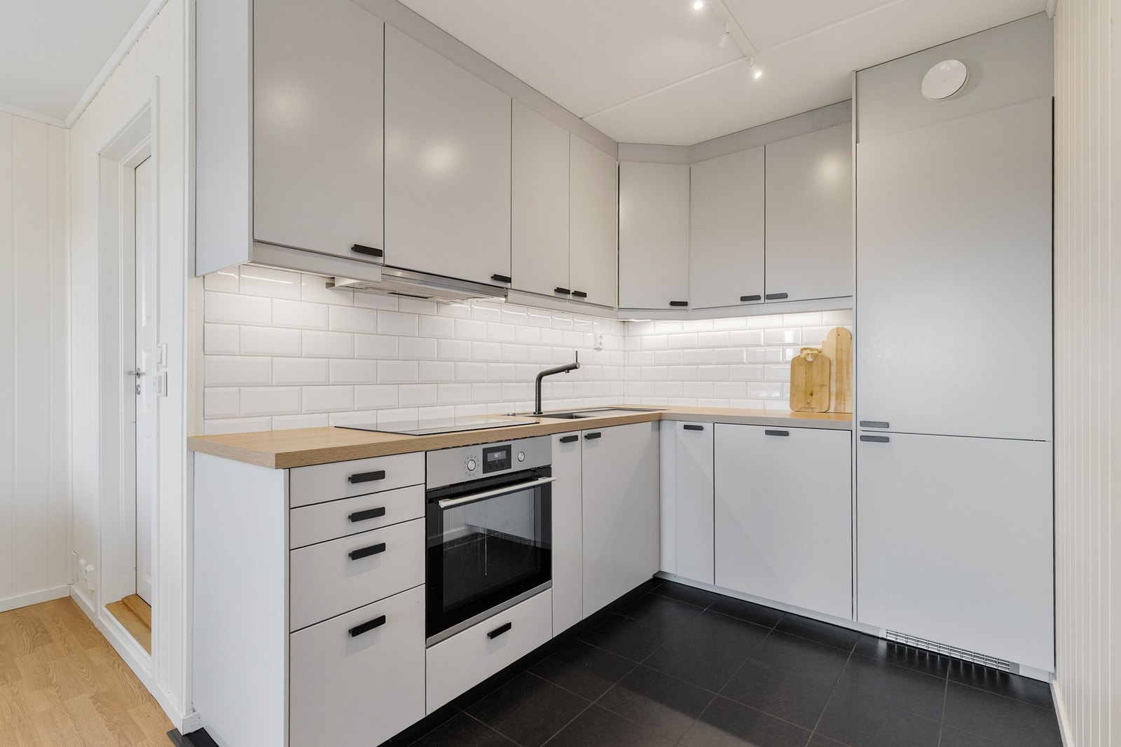 Pen kjøkkeninnredning med integrert stekeovn, platetopp, oppvaskmaskin og kjøleskap med fryser Galleribilde