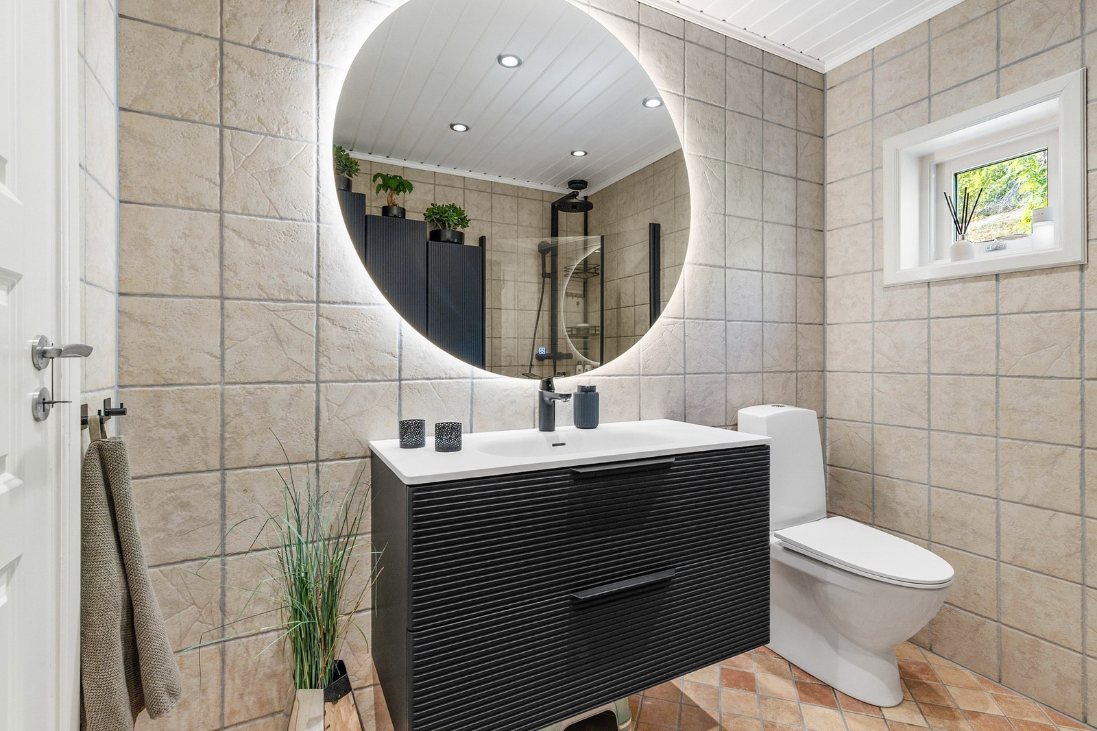 Rommet er utstyrt med dusjhjørne, gulvstående toalett, vegghengt servantinnredning og møbel for ekstra oppbevaring Galleribilde