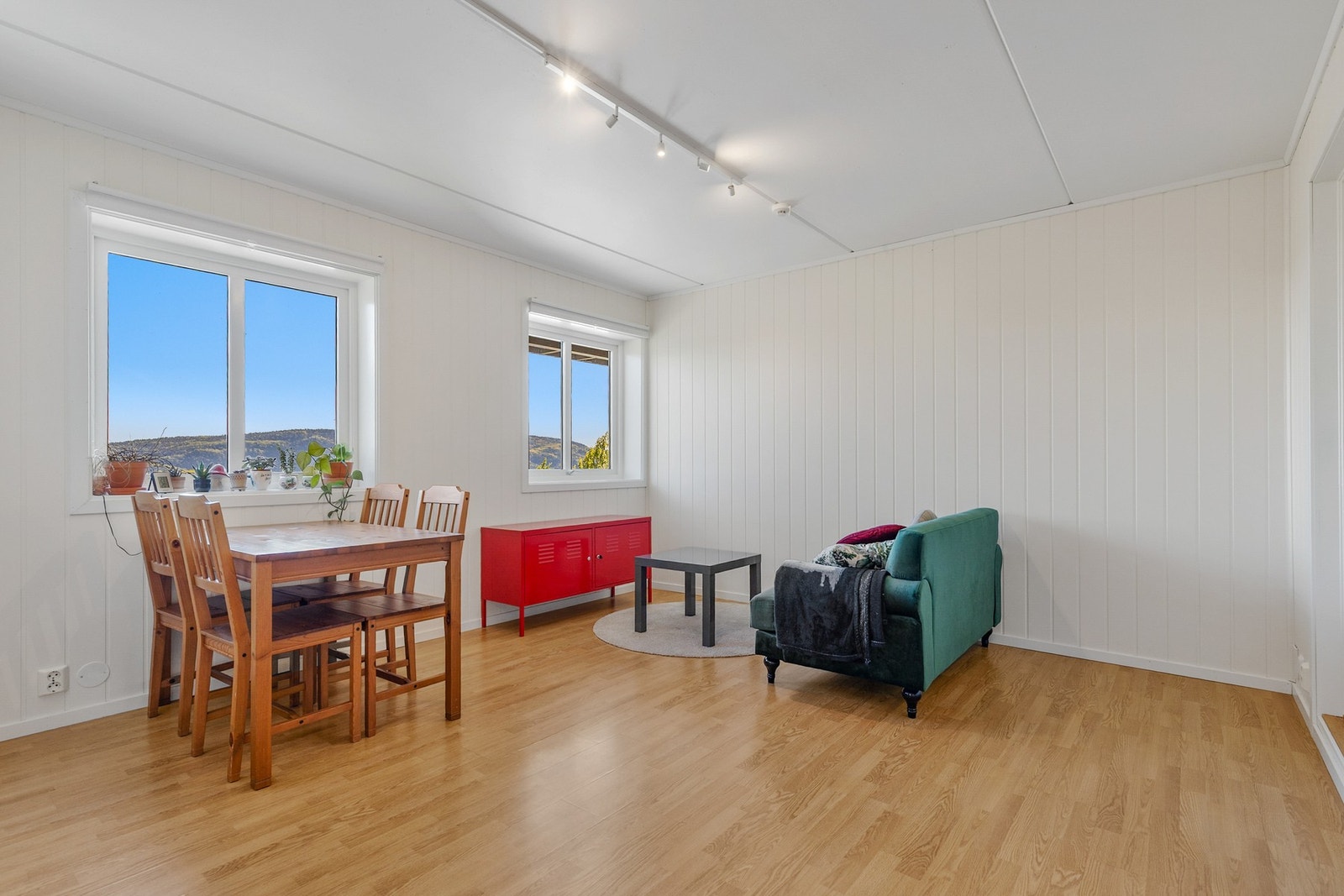 Lys og romslig stue med laminat på gulv, panelplater på vegger og slett flate i himling Galleribilde