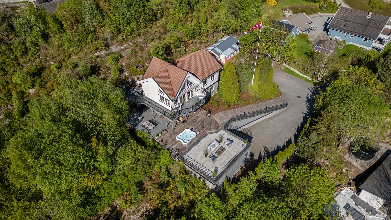 Skrånende tomt opparbeidet med asfaltert og stensatt oppkjørsel, plenareal, naturtomt og diverse beplantning Galleribilde