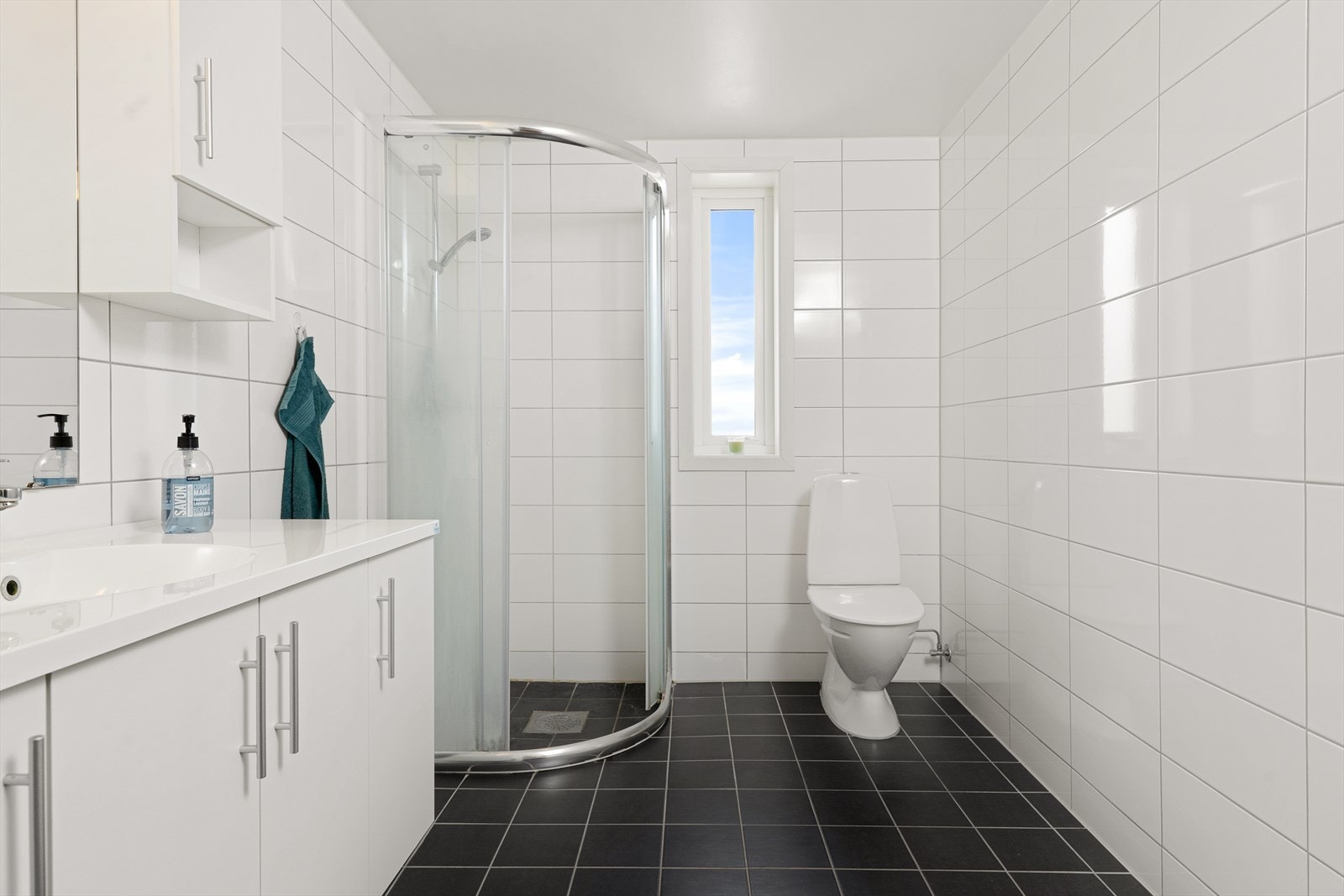 Bedet er med flislagt gulv og vegger. Rommet er utstyrt med toalett, dusj og servant i innredning. Galleribilde