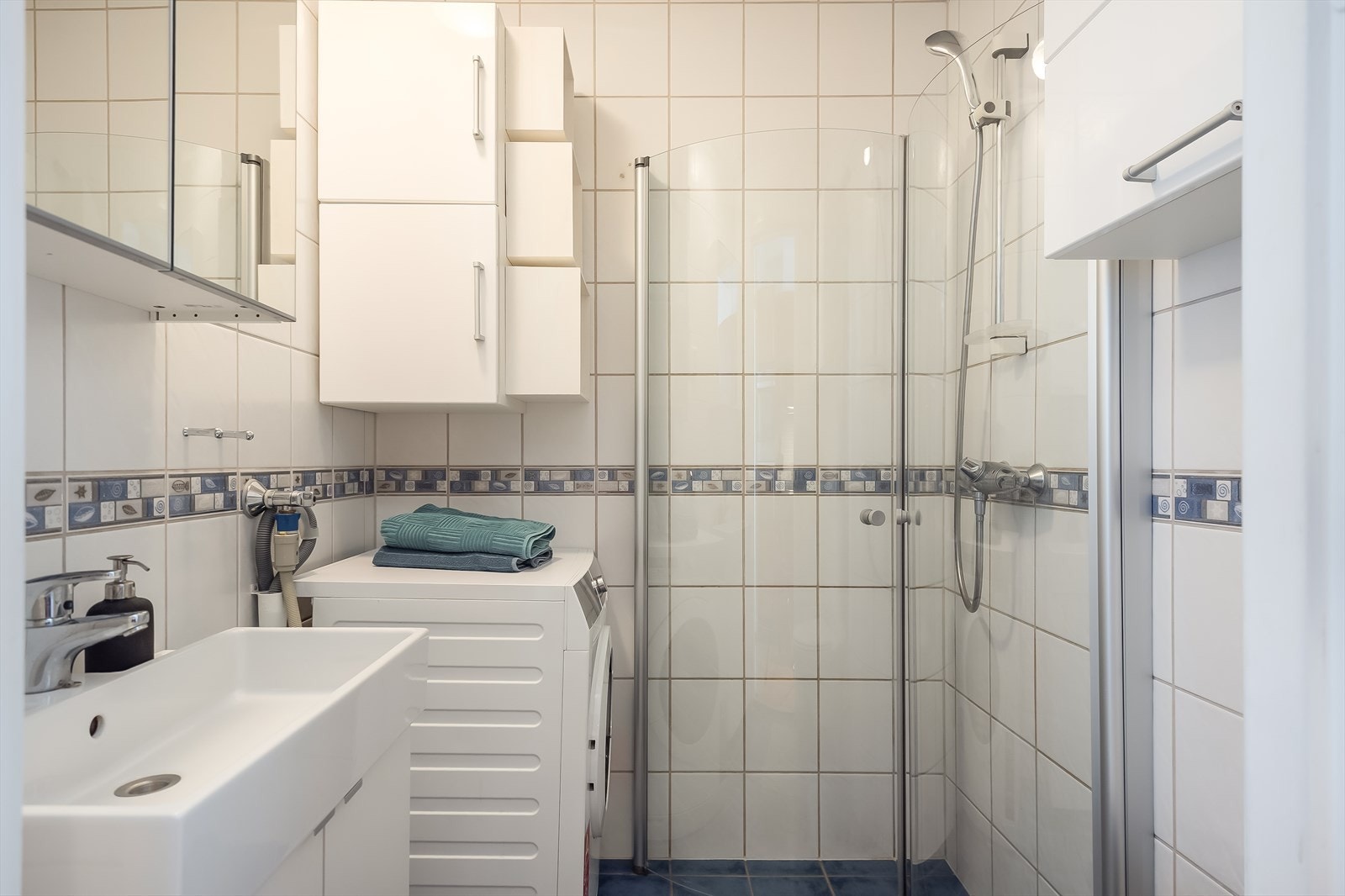 Lyst og flislagt bad med praktisk baderomsinnredning fra nyere byggeår. Galleribilde