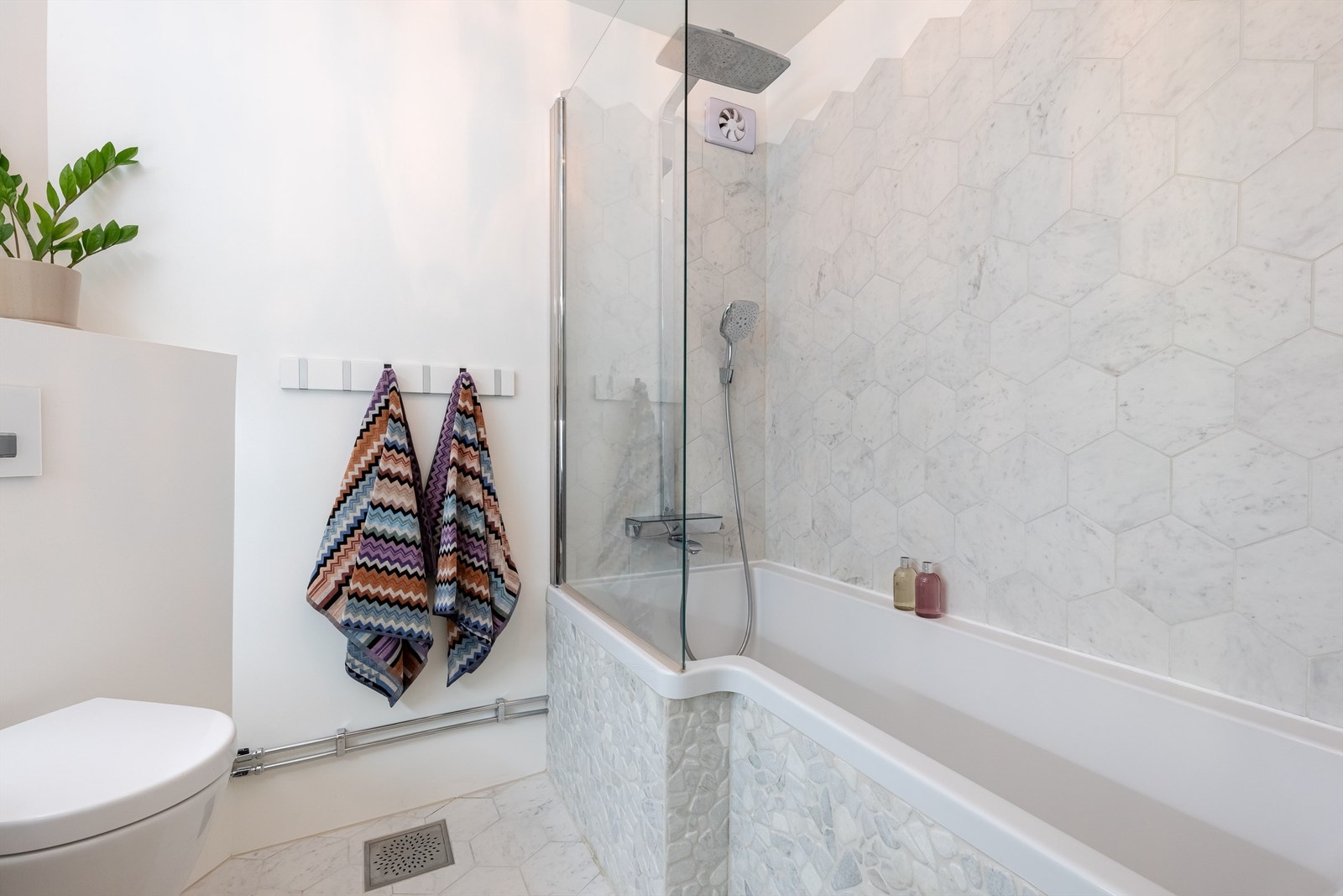 Videre har badet badekar med dusj og vegghengt klosett. Det er elektrisk styrt vifte. Galleribilde