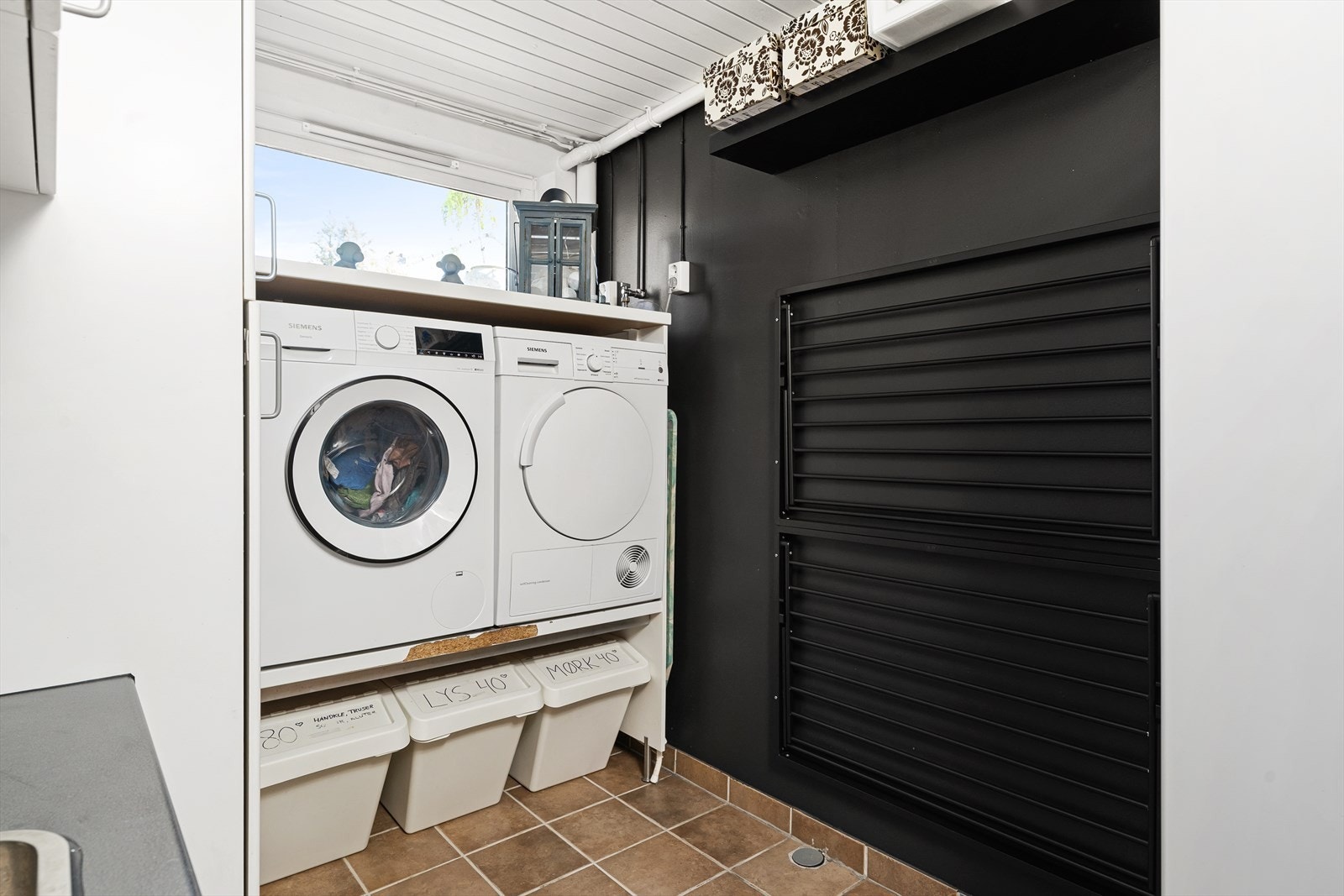 Vaskerommet er praktisk innredet med maskiner i arbeidshøyde og vegghengt tørkestativ. Galleribilde