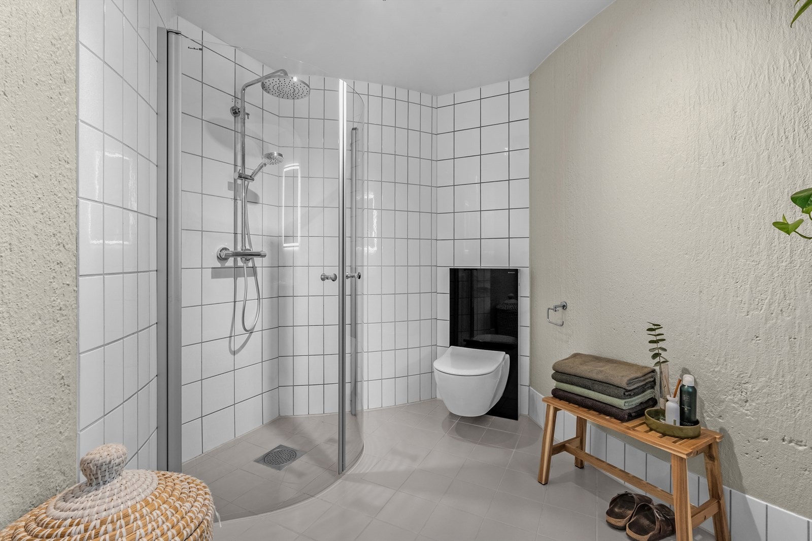 Det er speil med lysarmatur på vegg over servanten. Veggmontert toalett med utvendig sisterne. Dusjhjørne med glassdører, sluk i sone og dusjutstyr. Galleribilde