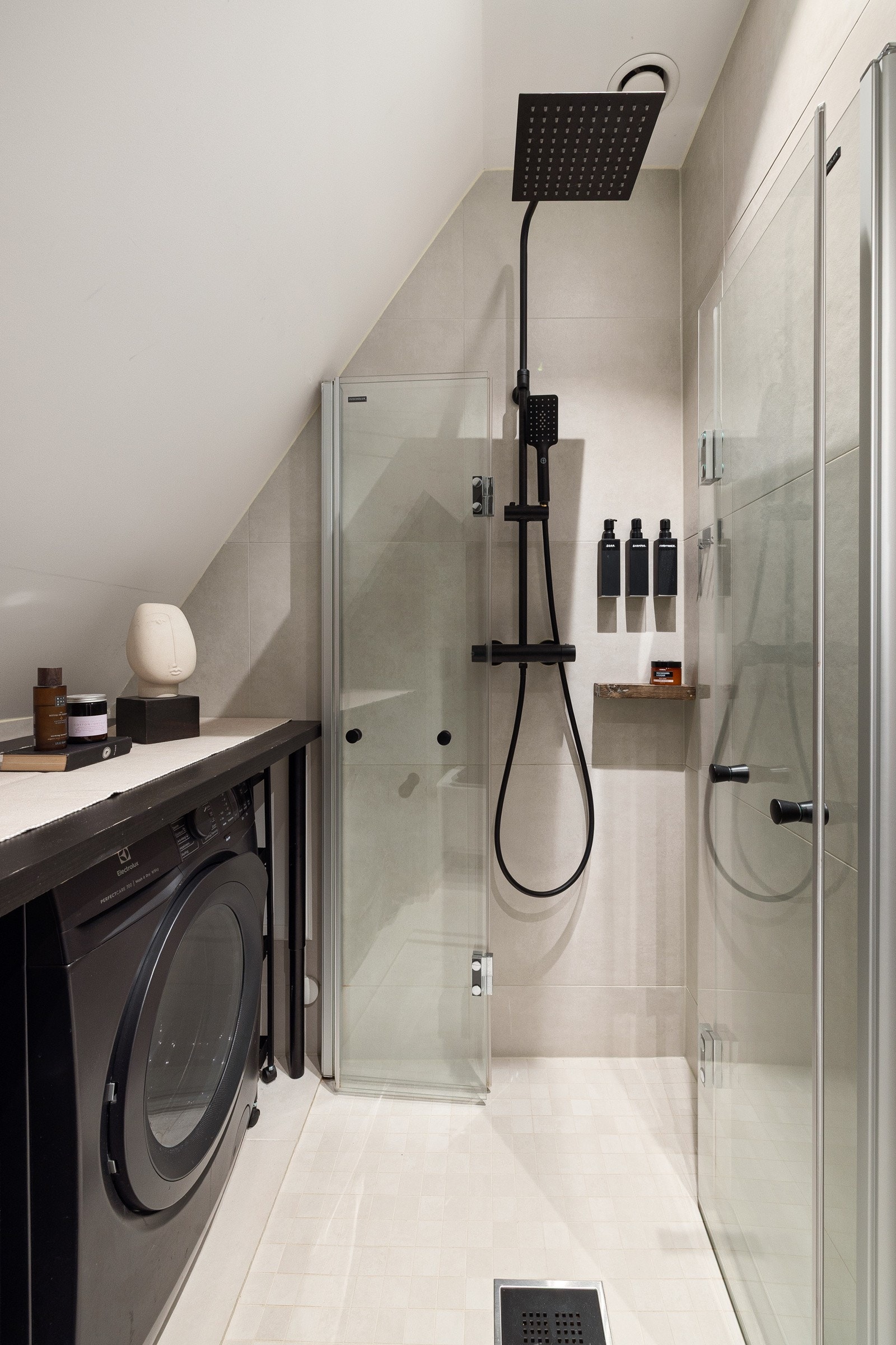 Baderommet er også utstyrt med dusjhjørne med innfellbare glassdører og sort armatur med både hånd- og regnfallsdusj, samt vegghengt toalett. Galleribilde