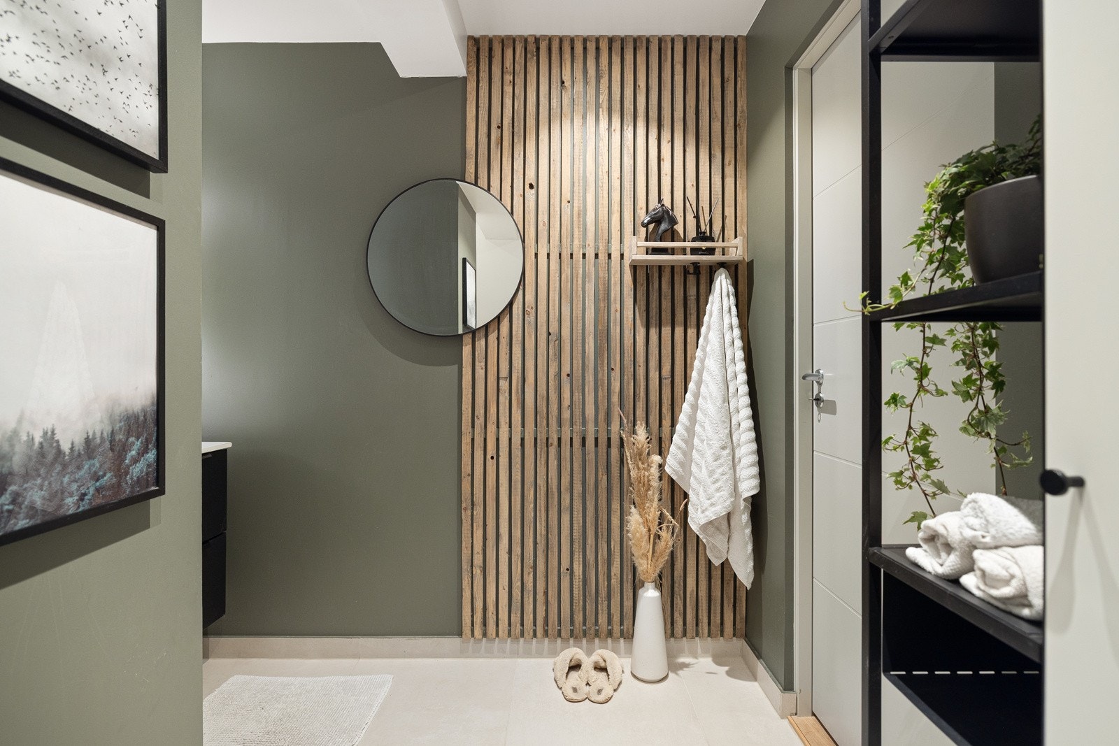 Leiligheten har et svært gjennomført og lekkert baderom fra 2019. Det er store lyse fliser på gulv med gulvvarme og glatte overflater malt i en mørk grønnfarge kombinert med fliser i dusjsonen. Galleribilde