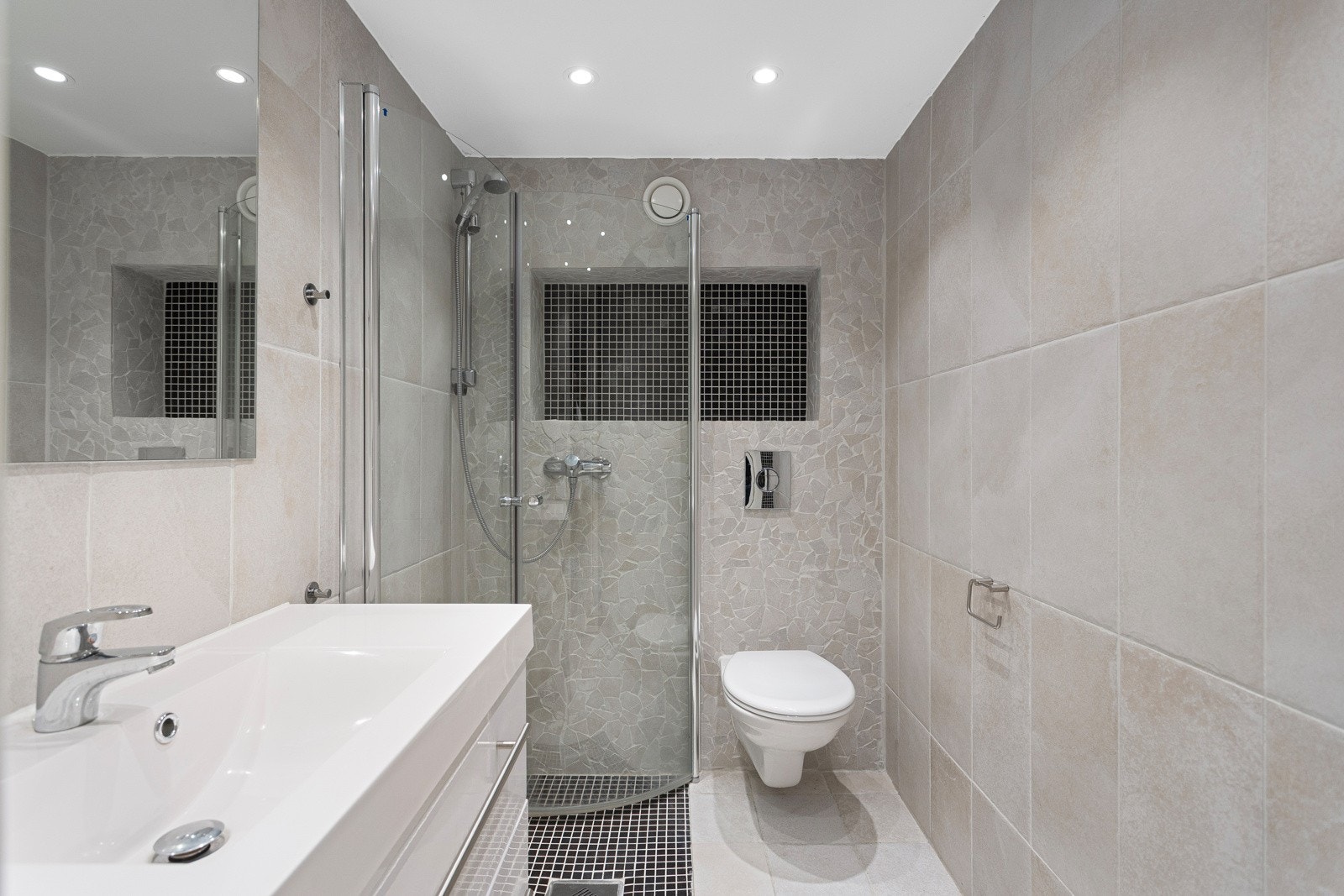 Badet i kjelleren har et moderne og rent uttrykk med vegghengt toalett, og nedfelt dusj Galleribilde