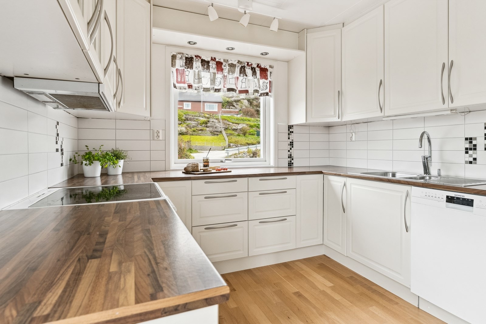 Eit klassisk og tidlaust kjøkken med kvite, profilerte frontar og mykje oppbevaringsplass med overskap til himling. Galleribilde