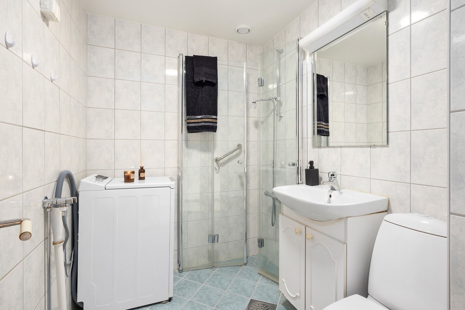 Badet har opplegg for vaskemaskin, vendbare dusjvegger, servantskap, speil og lys Galleribilde