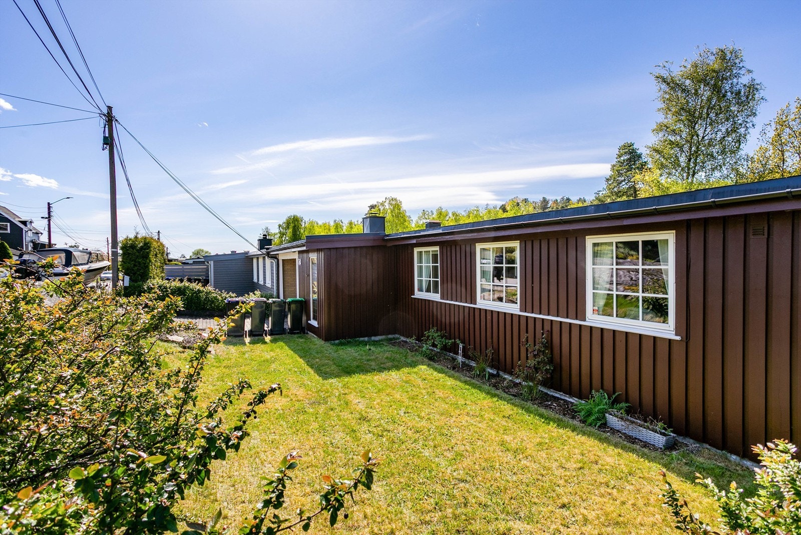 Pent opparbeidet hage er anlagt foran boligen, solfylt fra tidlig morgen sommerstid. Galleribilde