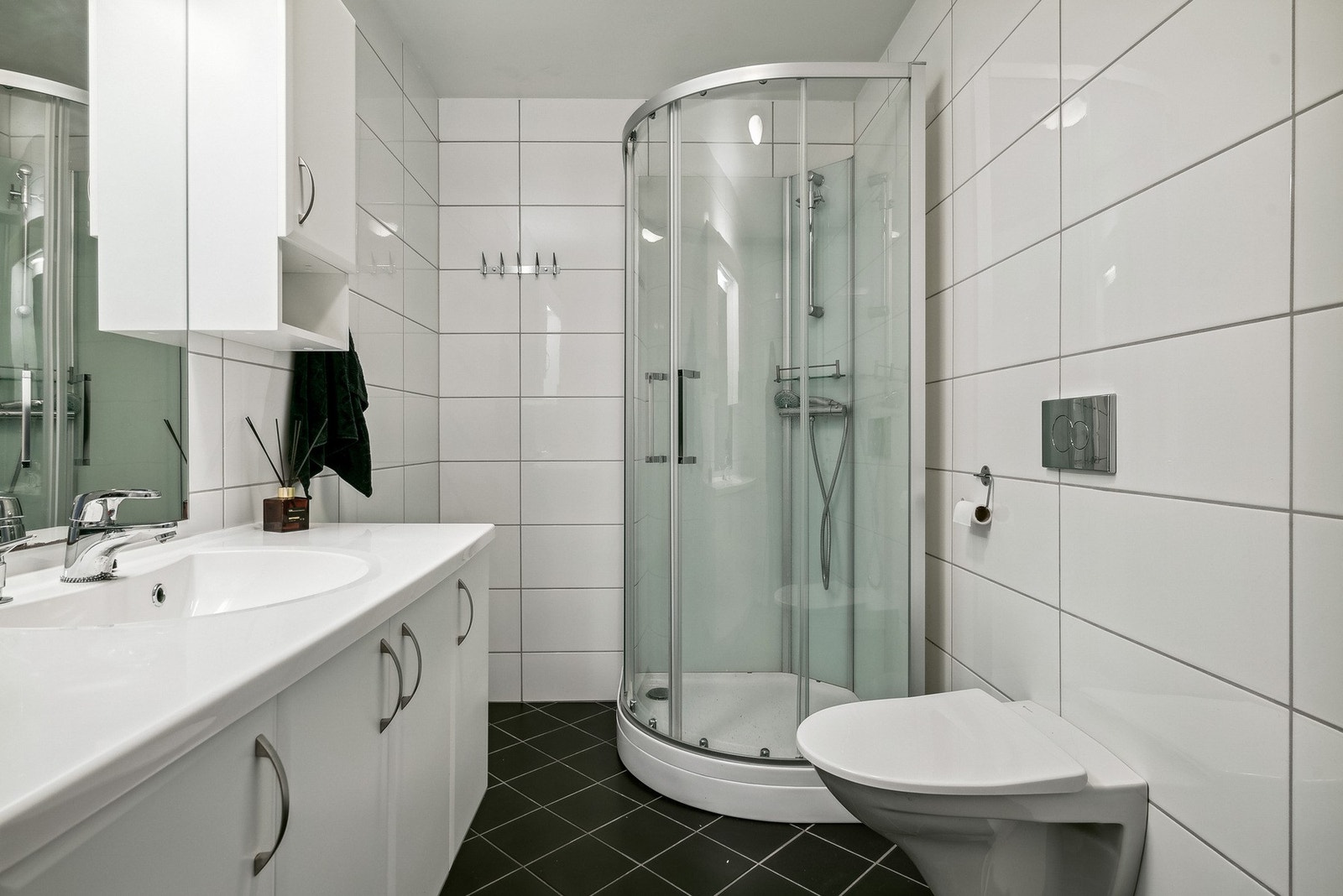 Baderommet er lyst og tidløst med flislagt gulv og varmekabler Galleribilde