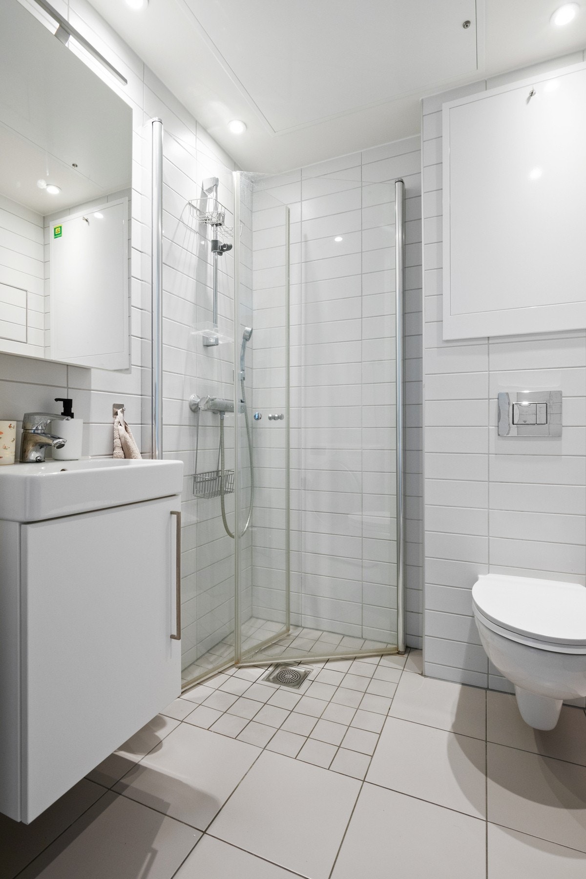 Baderomsinnredningen har hvit front og består av en heldekkende servant på en skapseksjon og et speilskap med belysning. Galleribilde