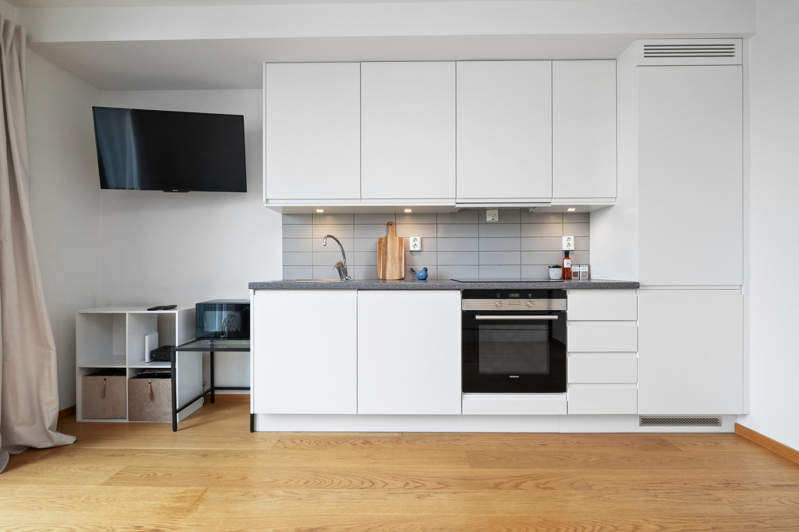 Innredningen har hvite, glatte fronter og grå laminatbenkeplate med nedfelt kum i stål. Galleribilde