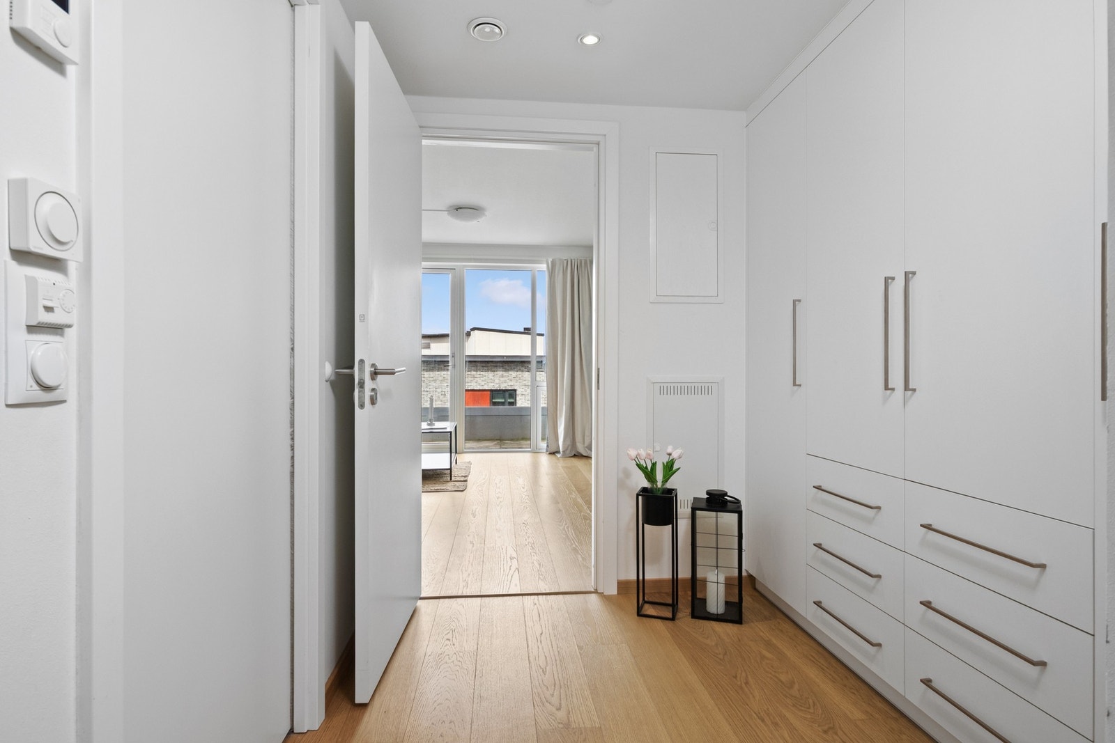 Langs den ene veggen er det montert takhøye garderobeskap med hvite fronter og flere skuffer, noe som gjør det enkelt å holde orden. Galleribilde