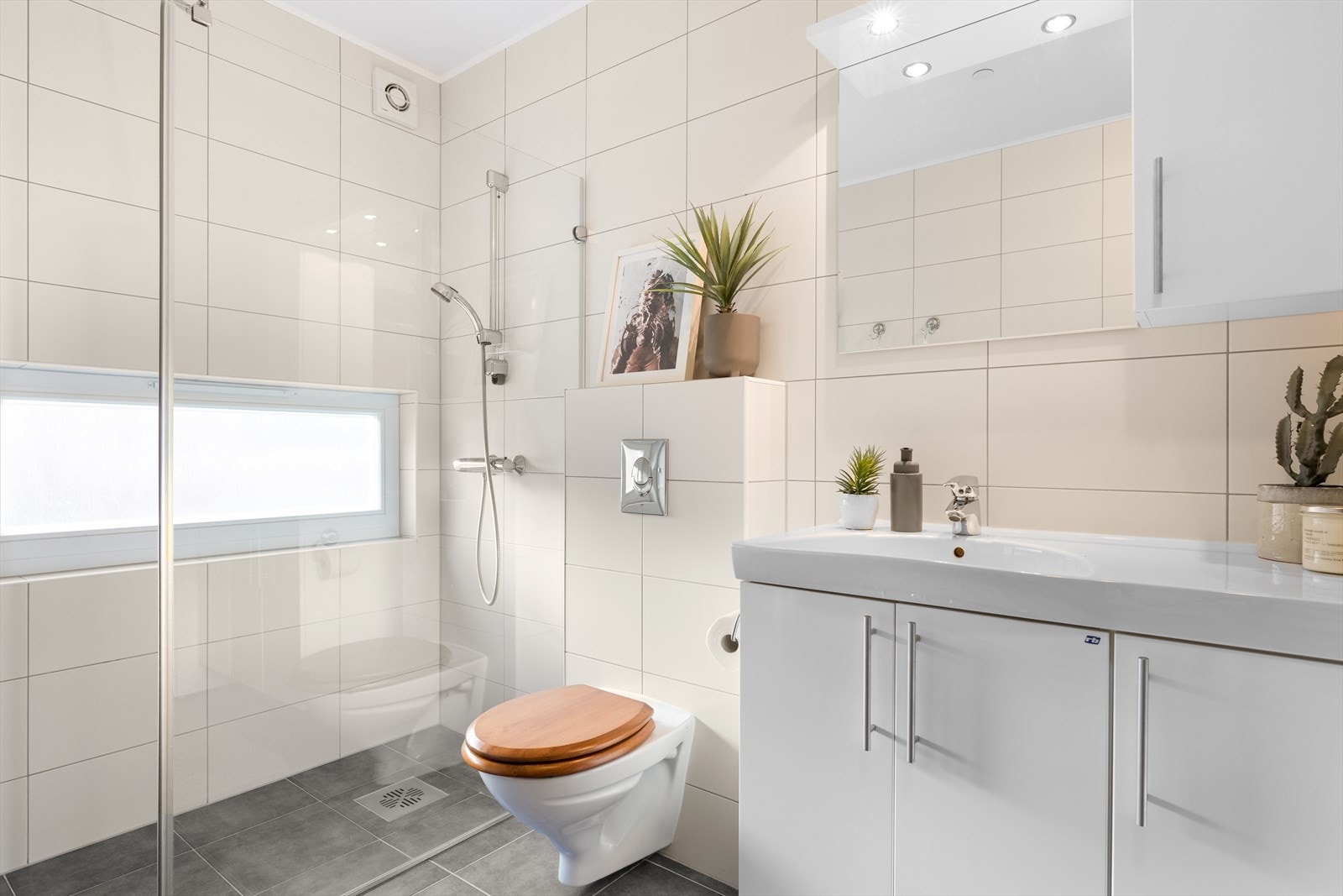 Baderomsinnredning med servantskap, overskap, høyskap, speil og lys over speilet. Opplegg for vaskemaskin. Galleribilde